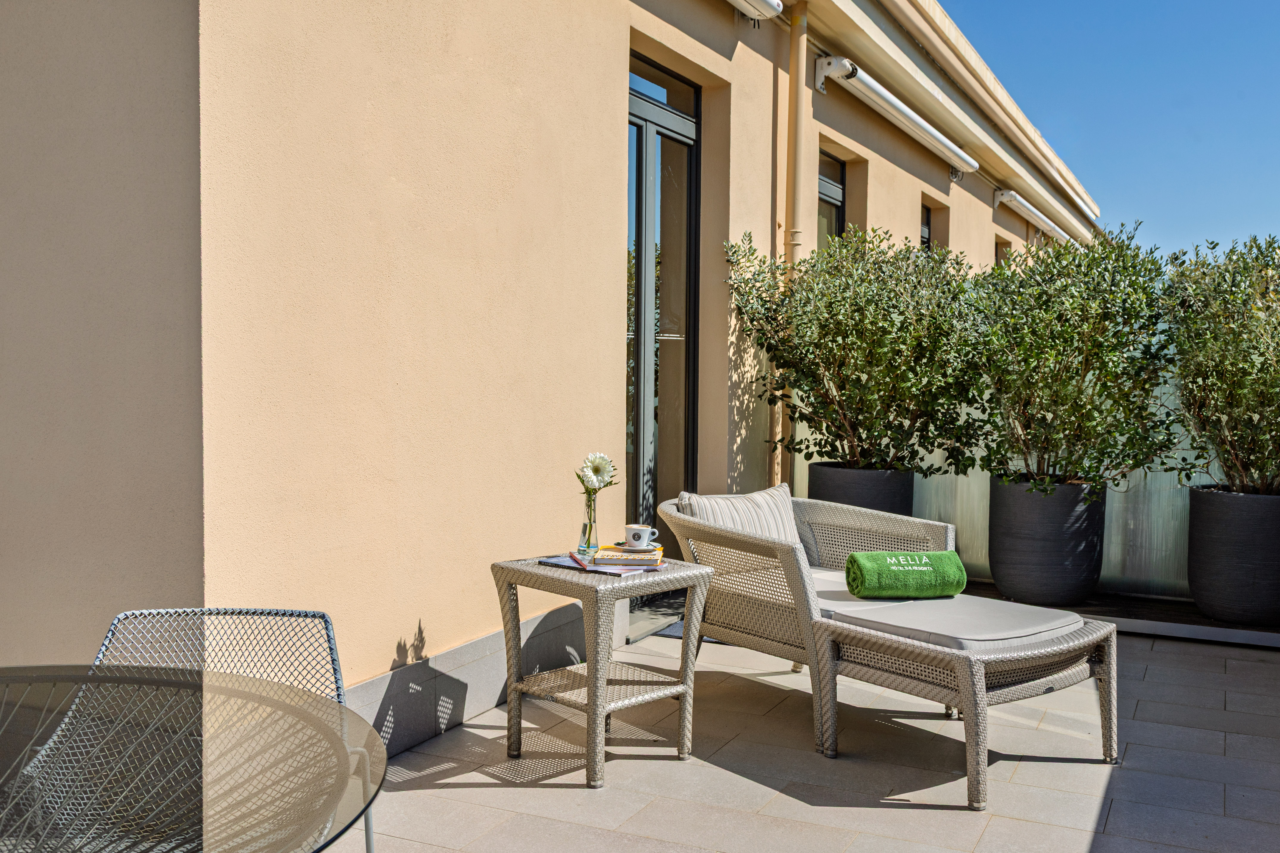 Meliá resort balcony with lounge chair, table, and potted plants. - Grand Suite met Terras - Meliá Genova, Genua
