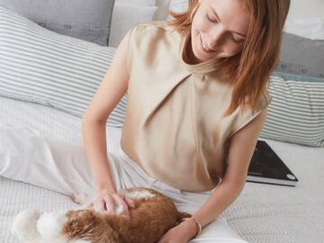 a woman sitting on a bed petting a dog