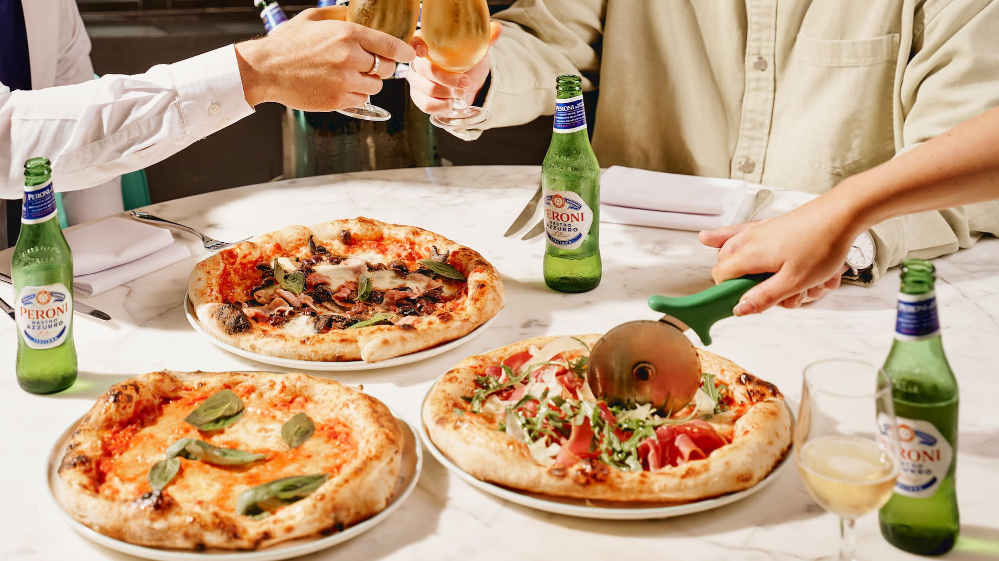 a group of people sitting at a table with pizzas and drinks