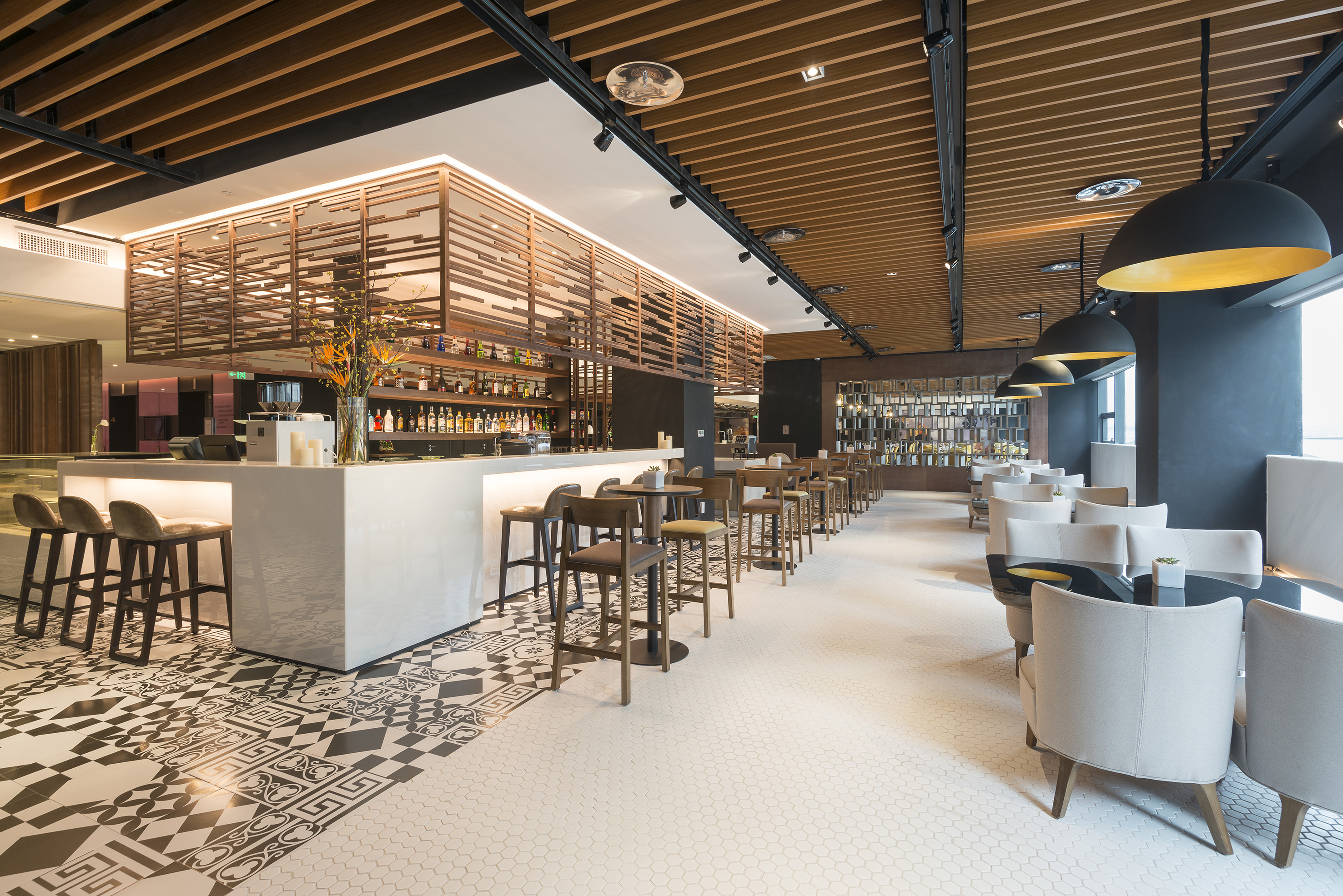 Modern bar interior with sleek counter, geometric floor, and contemporary lighting.
