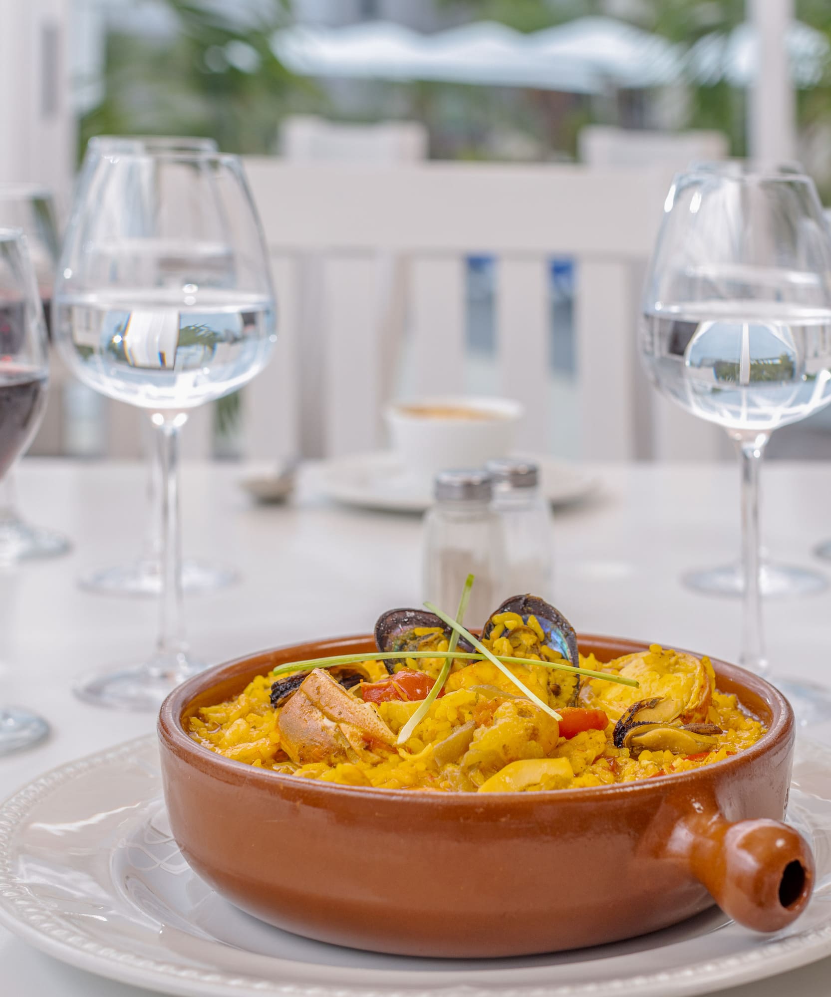 a bowl of food on a table with wine glasses