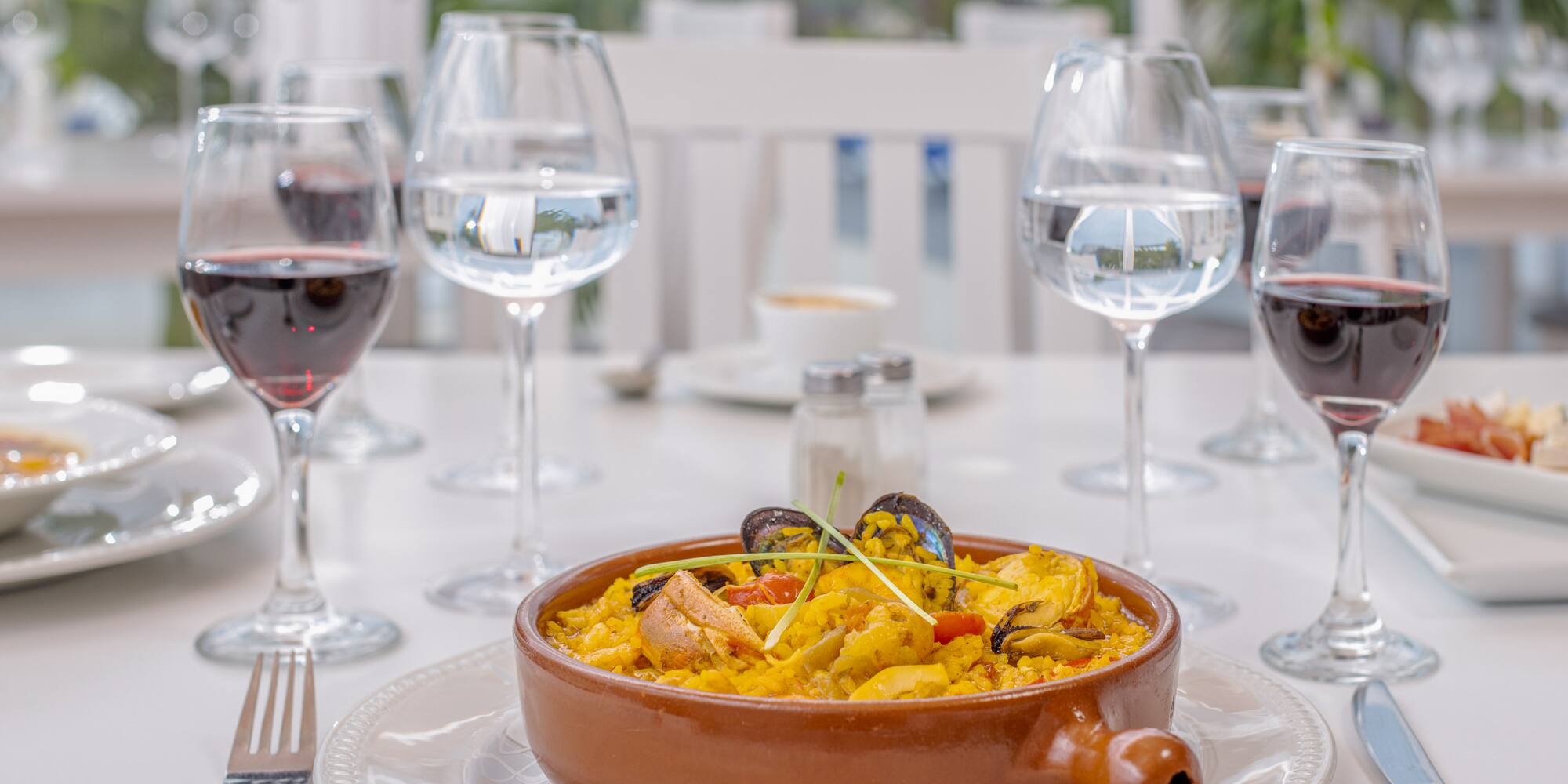 a bowl of food on a table with wine glasses