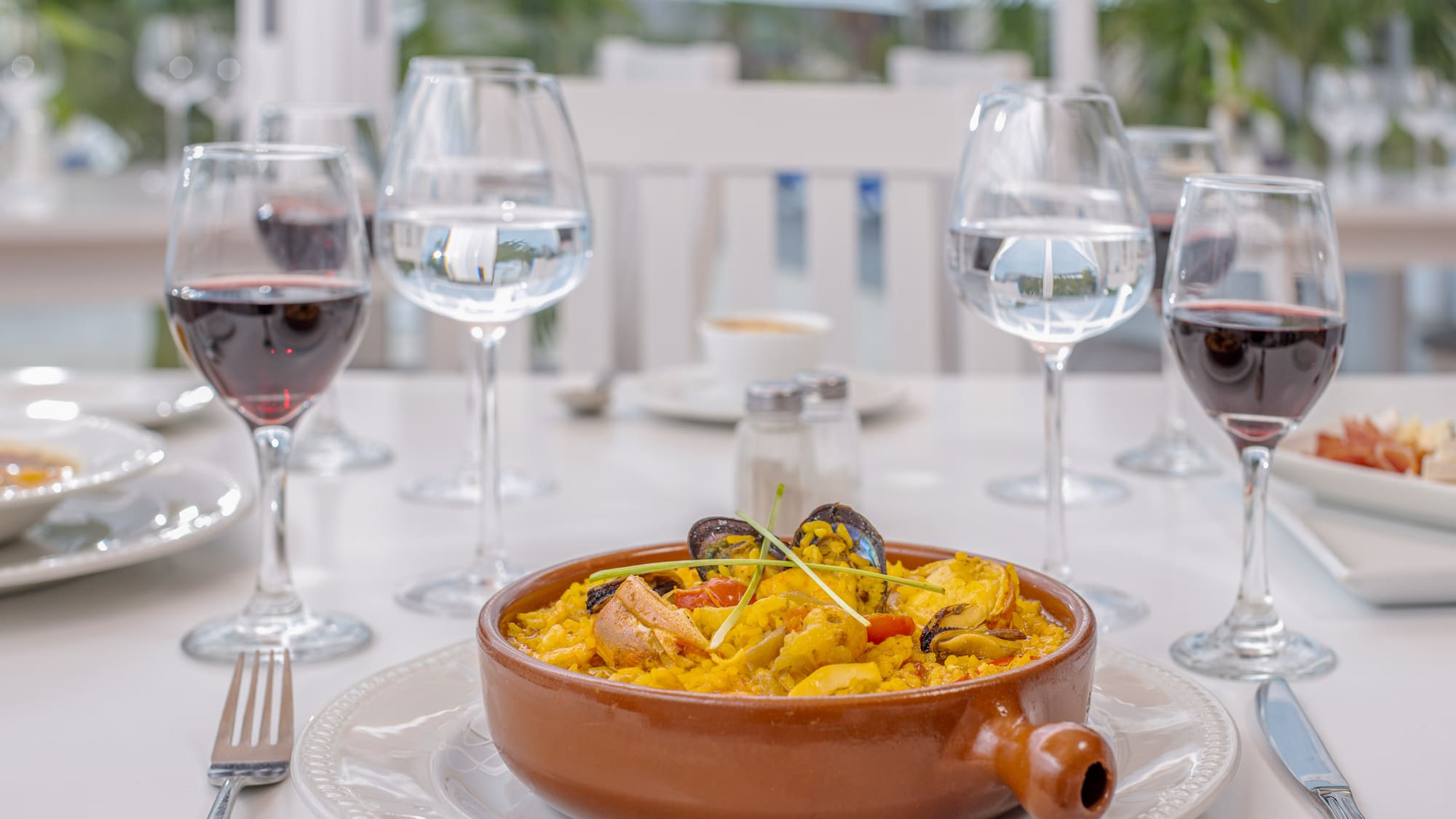 a bowl of food on a table with wine glasses