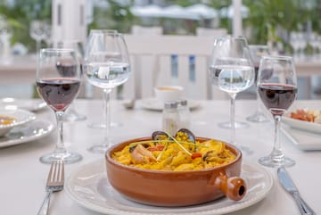 a bowl of food on a table with wine glasses