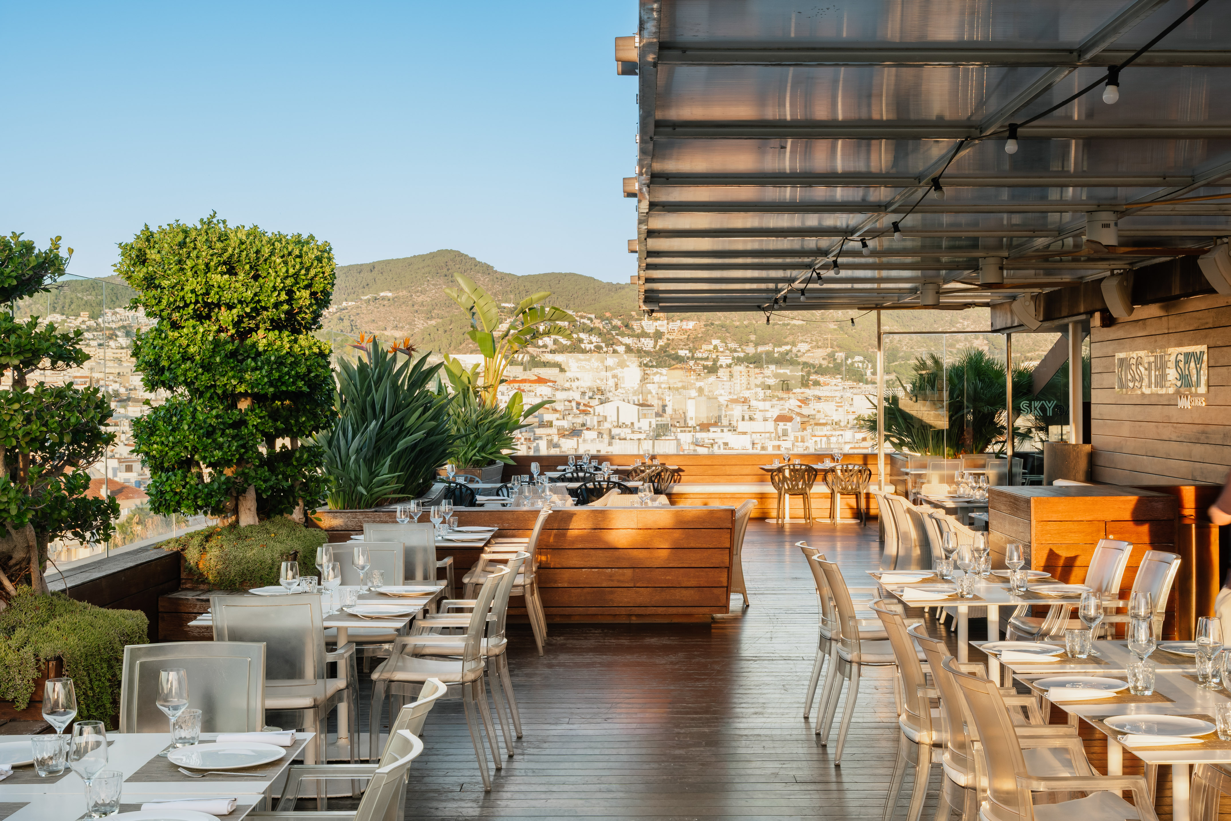 Rooftop dining terrace with modern seating, city view, and mountain backdrop. - スカイバー, バー - MiM Sitges Meliá Collection, シッチェス