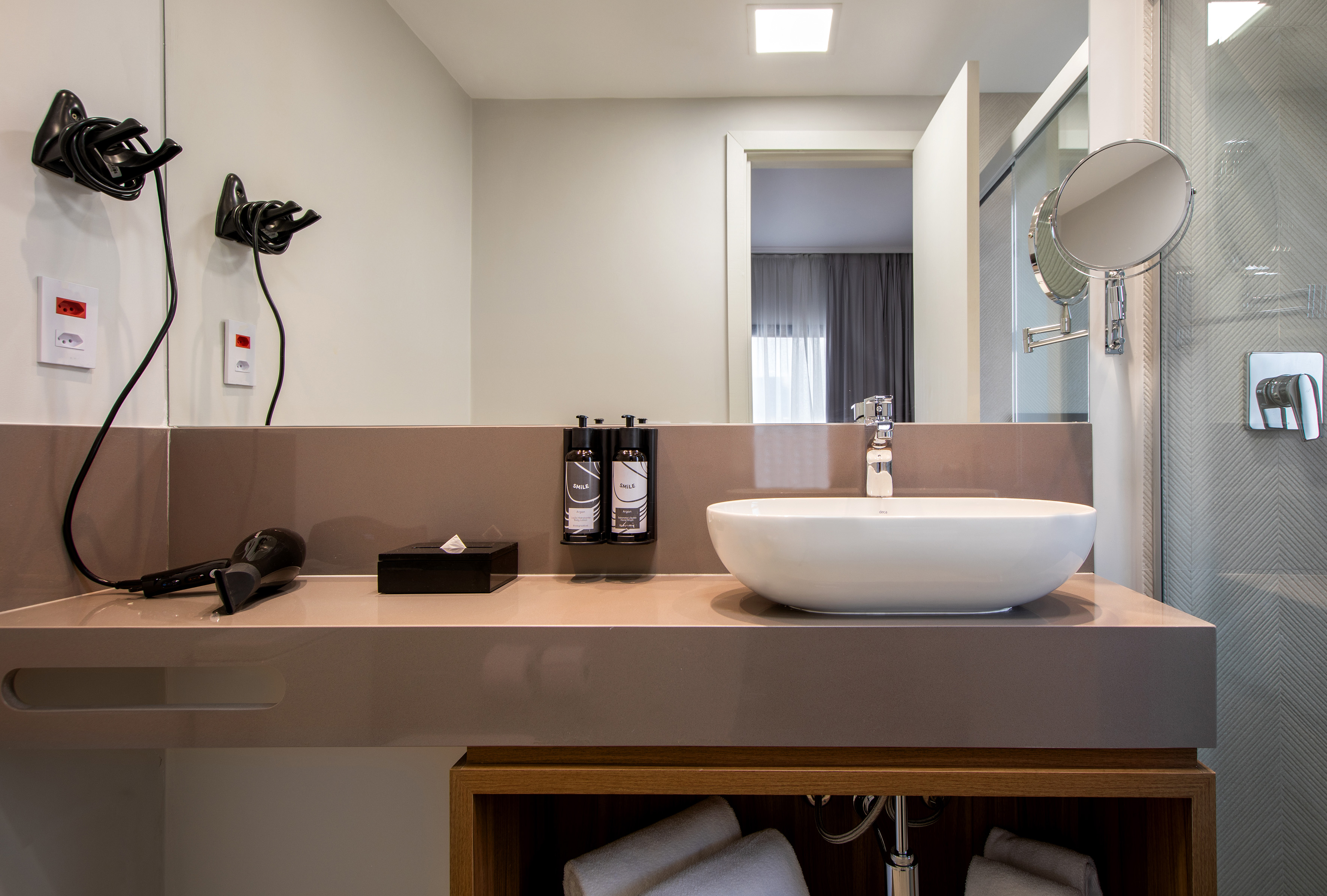 Modern hotel bathroom vanity with sink, hairdryer, and toiletries.