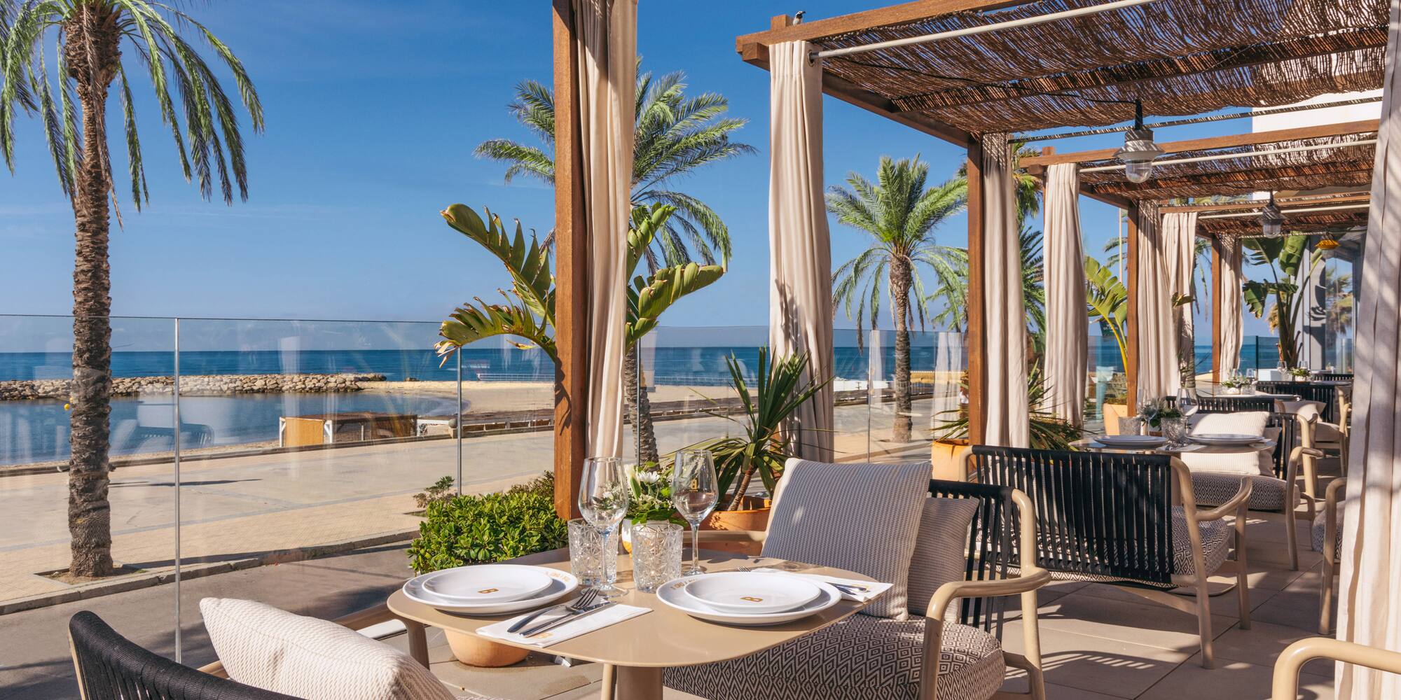 a table set up on a patio with palm trees and a beach