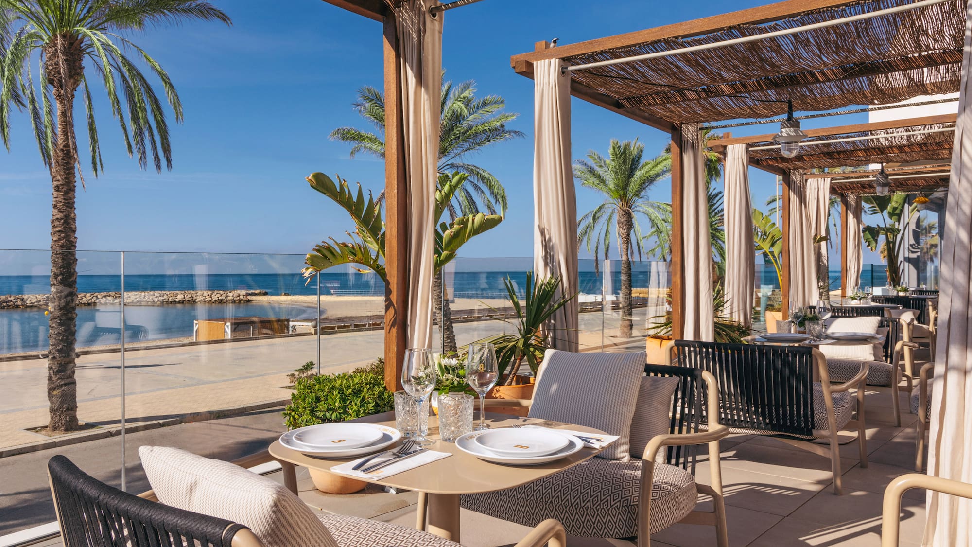 a table set up on a patio with palm trees and a beach