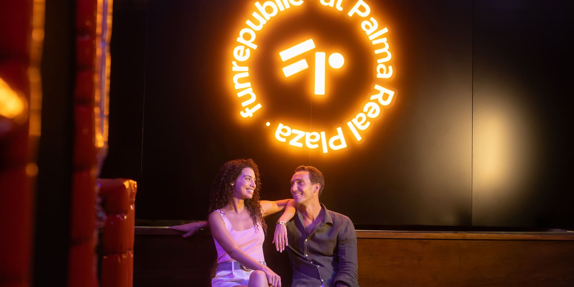 Smiling couple under Funrepublic at Palma Real Plaza neon sign.