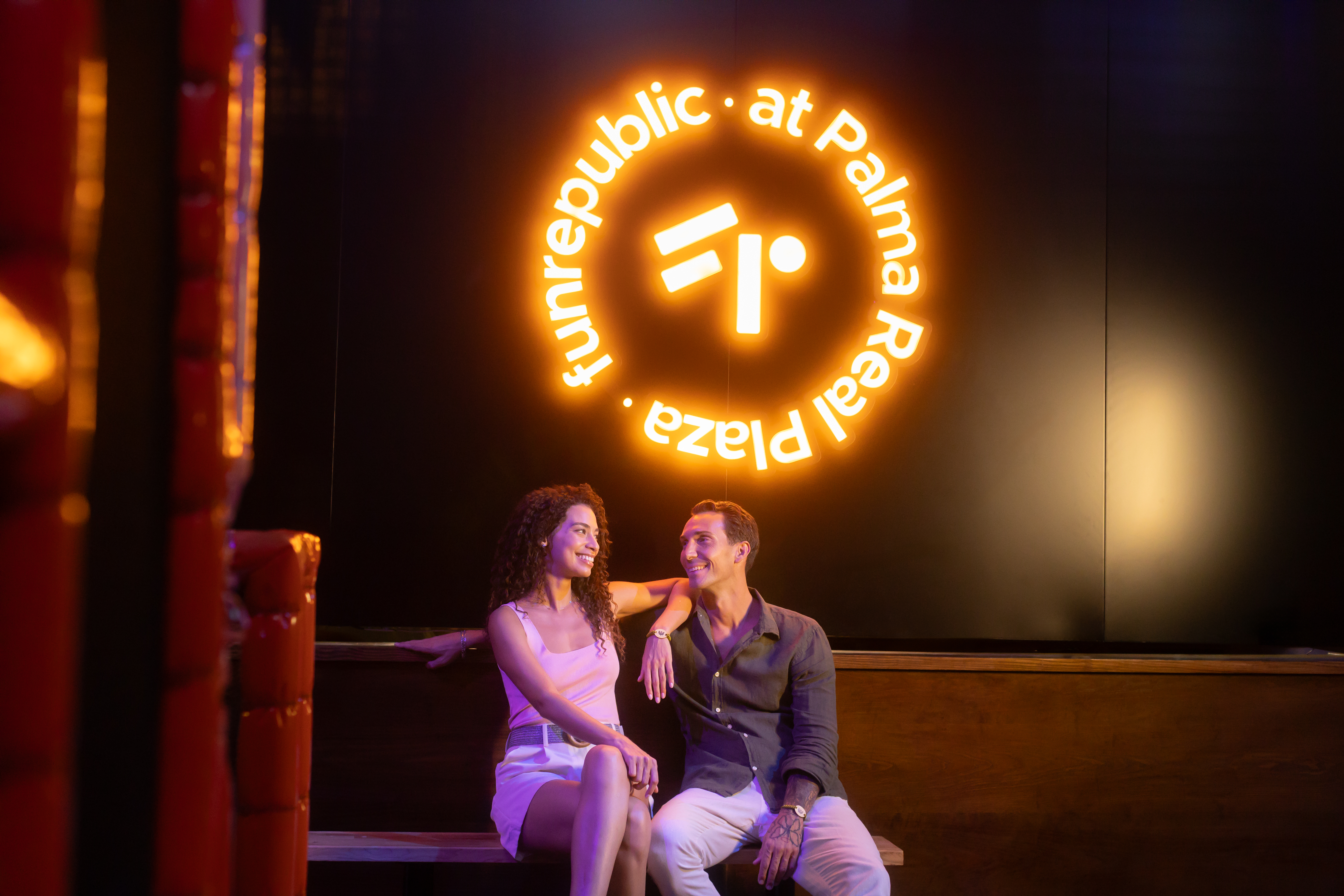 Smiling couple under Funrepublic at Palma Real Plaza neon sign.