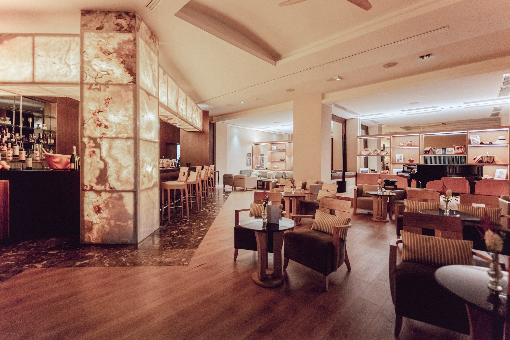 Luxurious hotel bar lounge featuring backlit onyx, cozy seating, and a grand piano.