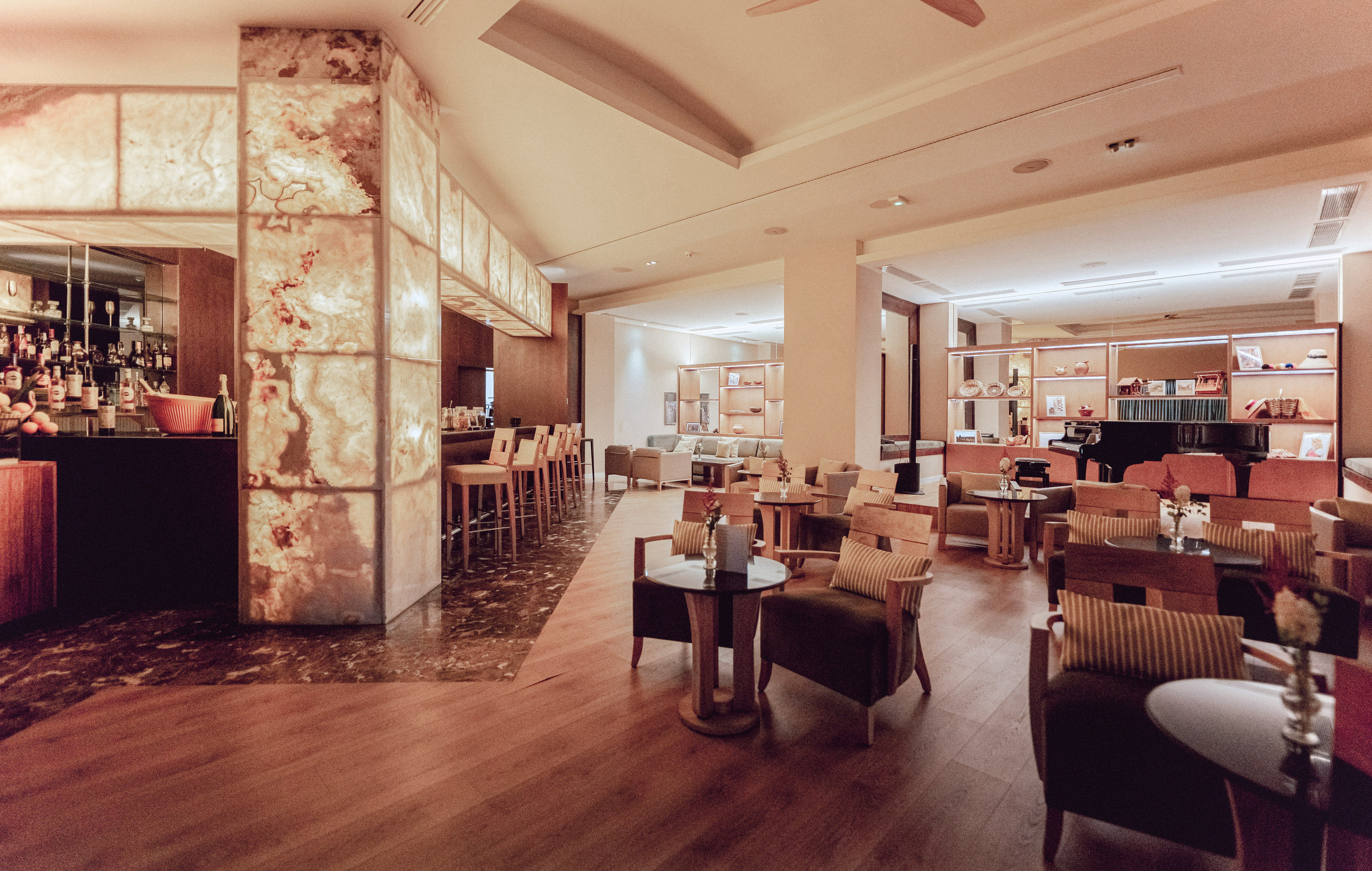 Luxurious hotel bar lounge featuring backlit onyx, cozy seating, and a grand piano.