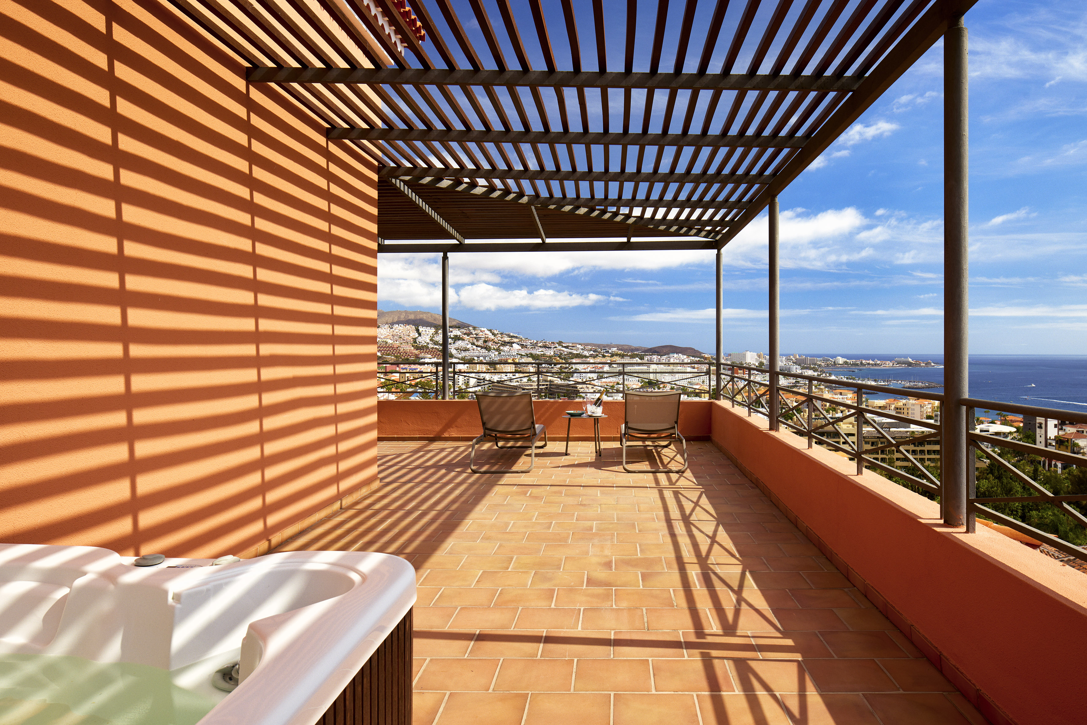 Luxury terrace with hot tub, ocean view, coastal town, and pergola.