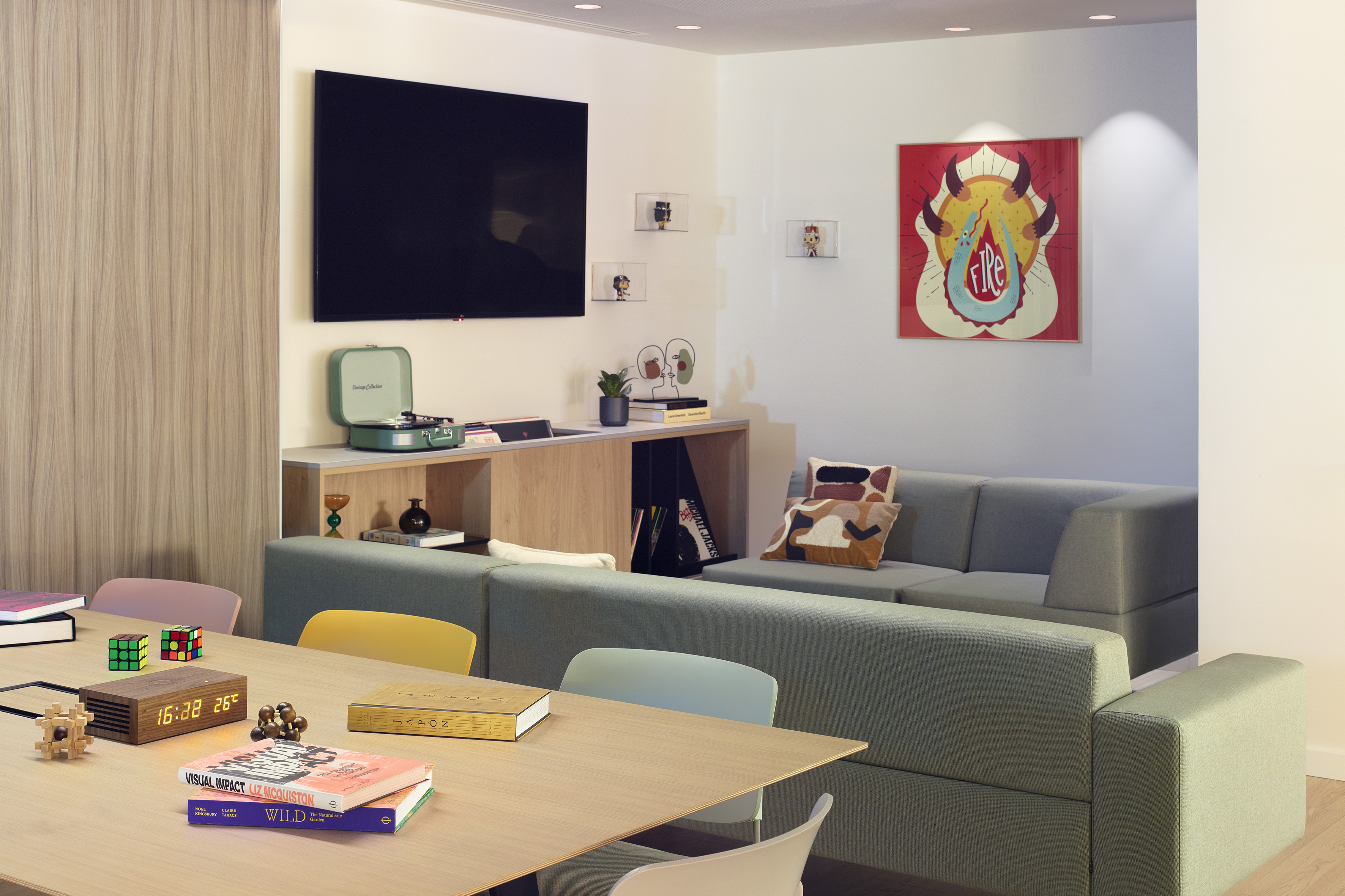 Modern lounge with large TV, modular green sofa, and wooden table.