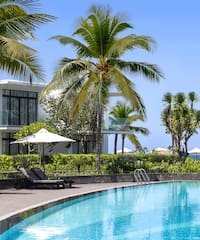 a swimming pool with palm trees and a building