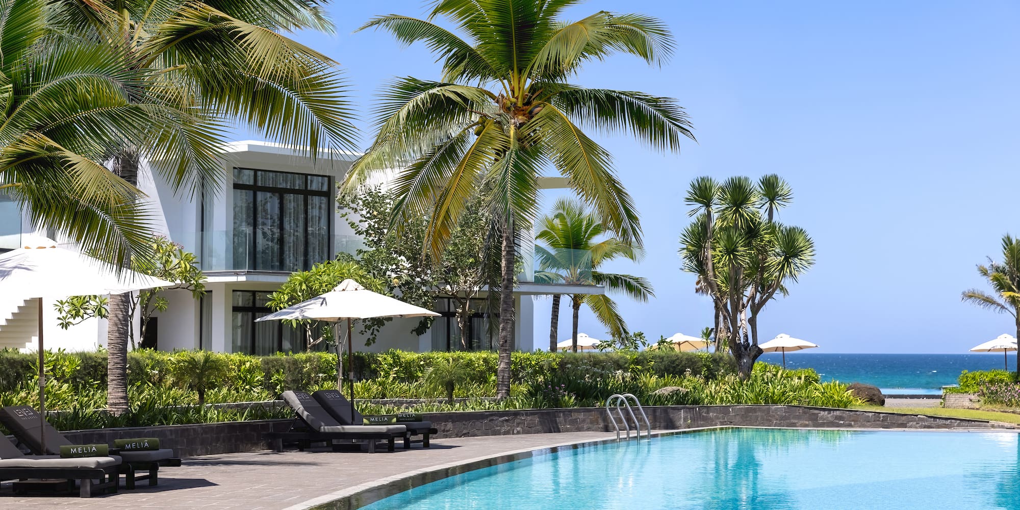 a swimming pool with palm trees and a building