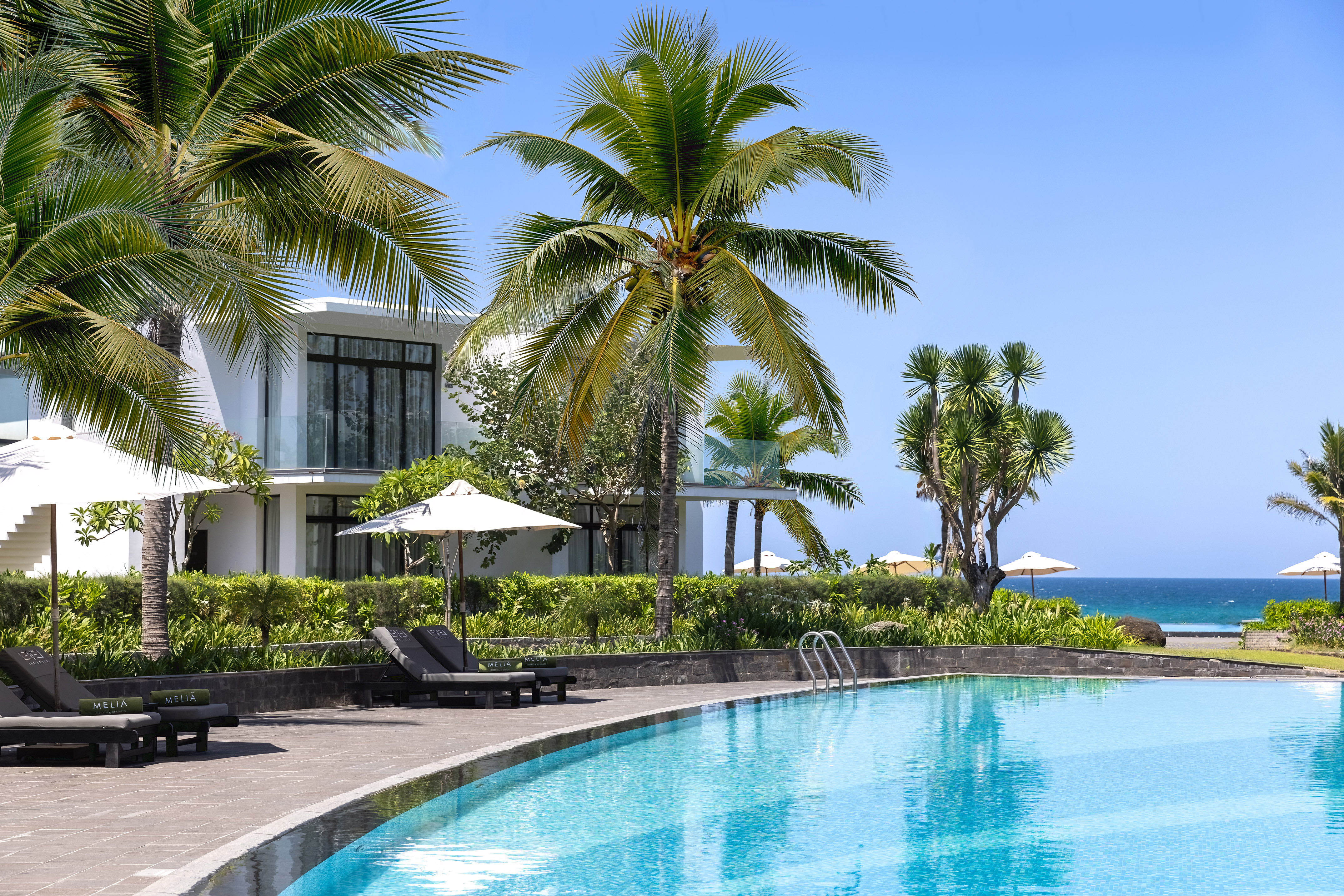 a swimming pool with palm trees and a building