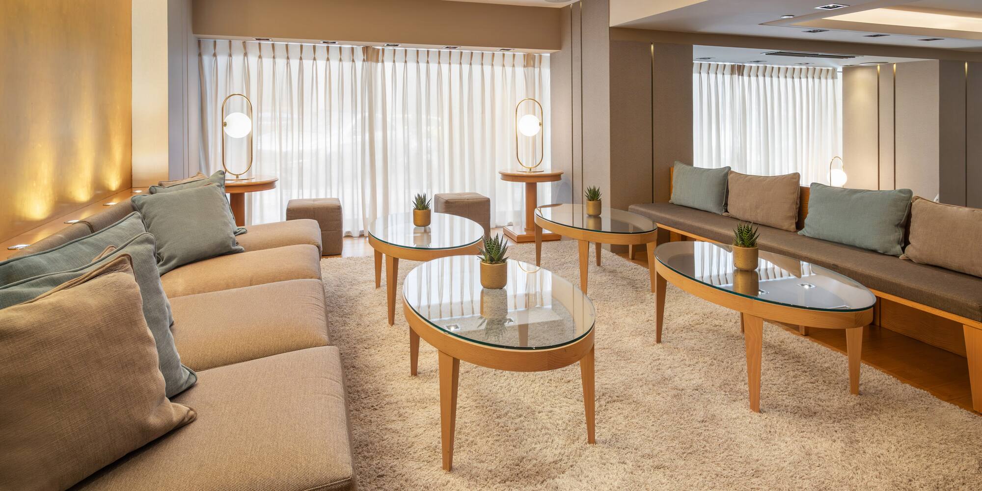 Modern hotel lounge: plush sofas, glass tables, shag rug, and warm lighting.