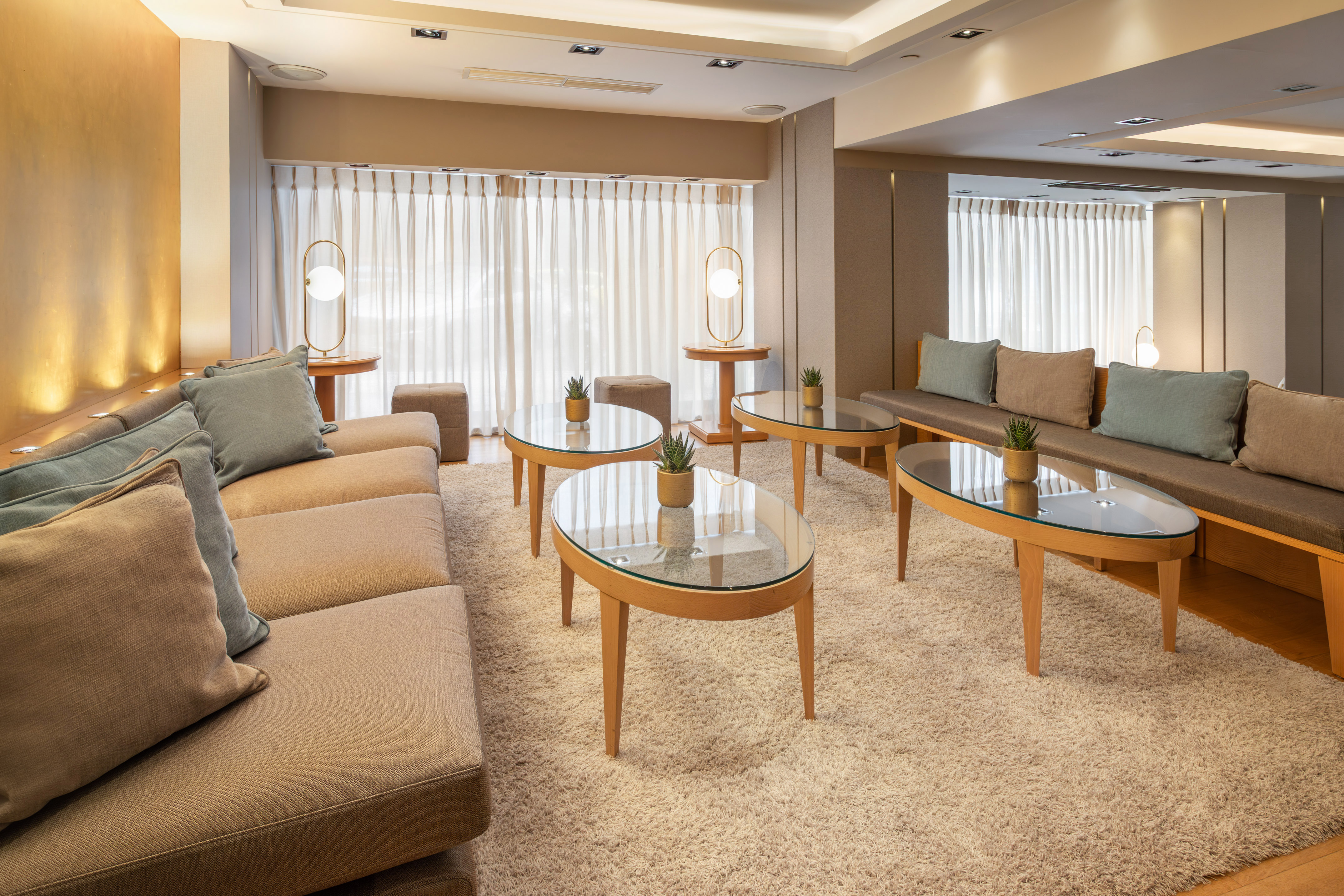 Modern hotel lounge: plush sofas, glass tables, shag rug, and warm lighting.