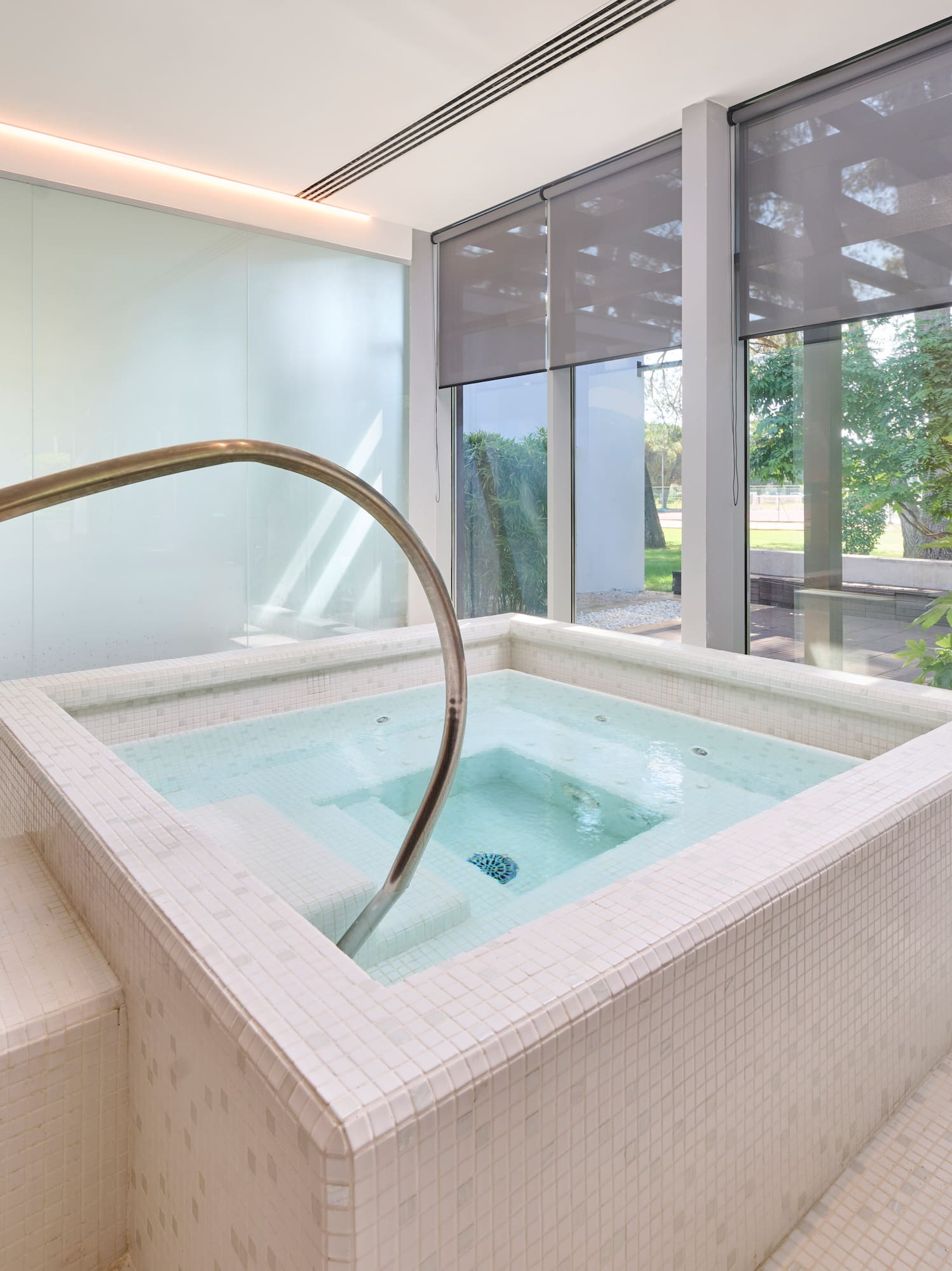 a jacuzzi with a staircase in a room with windows