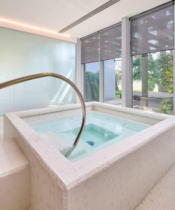 a jacuzzi with a staircase in a room with windows