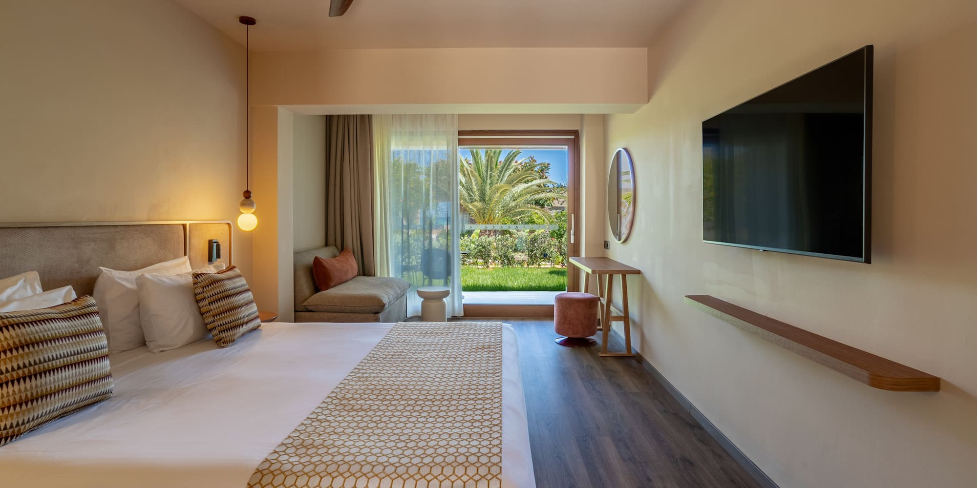 Contemporary hotel bedroom with a large bed, balcony garden view, and TV.