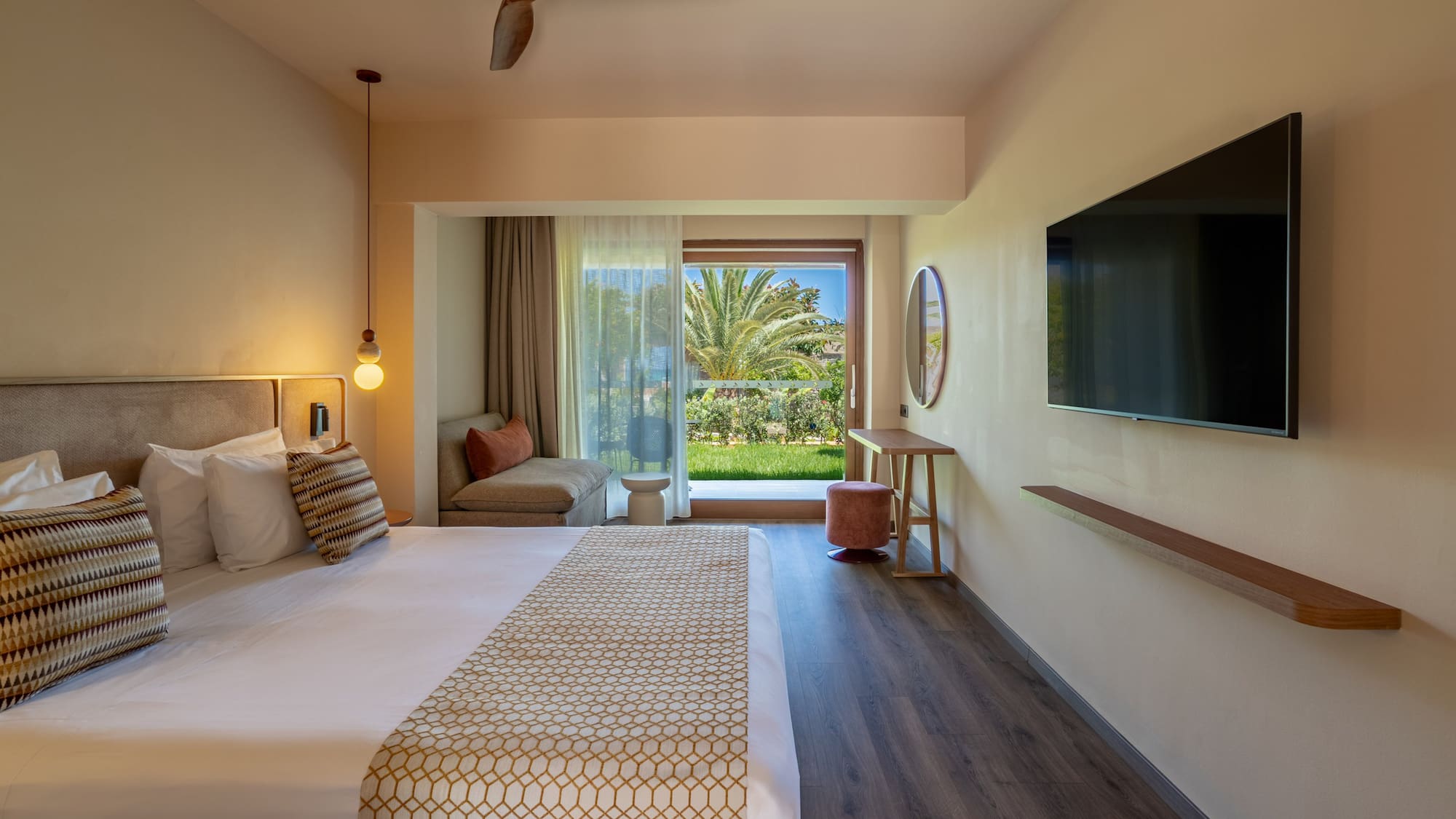 Contemporary hotel bedroom with a large bed, balcony garden view, and TV.