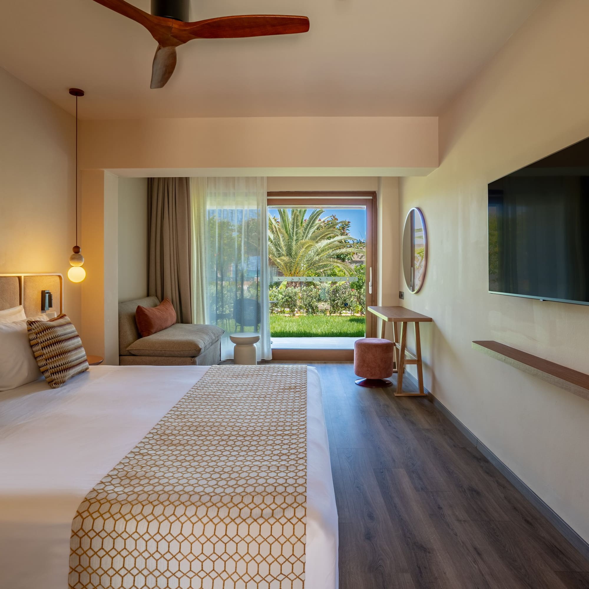 Contemporary hotel bedroom with a large bed, balcony garden view, and TV.