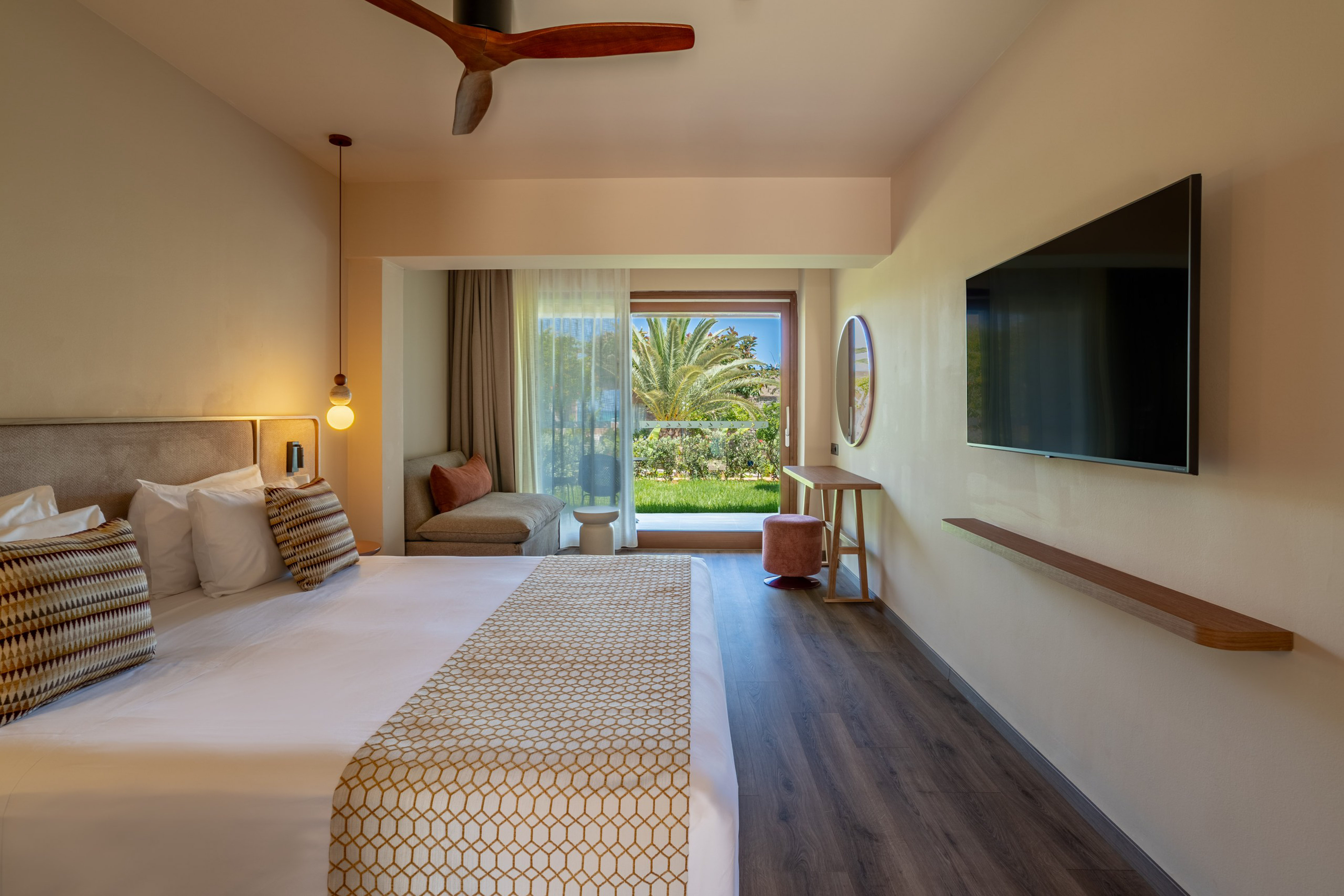 Contemporary hotel bedroom with a large bed, balcony garden view, and TV.