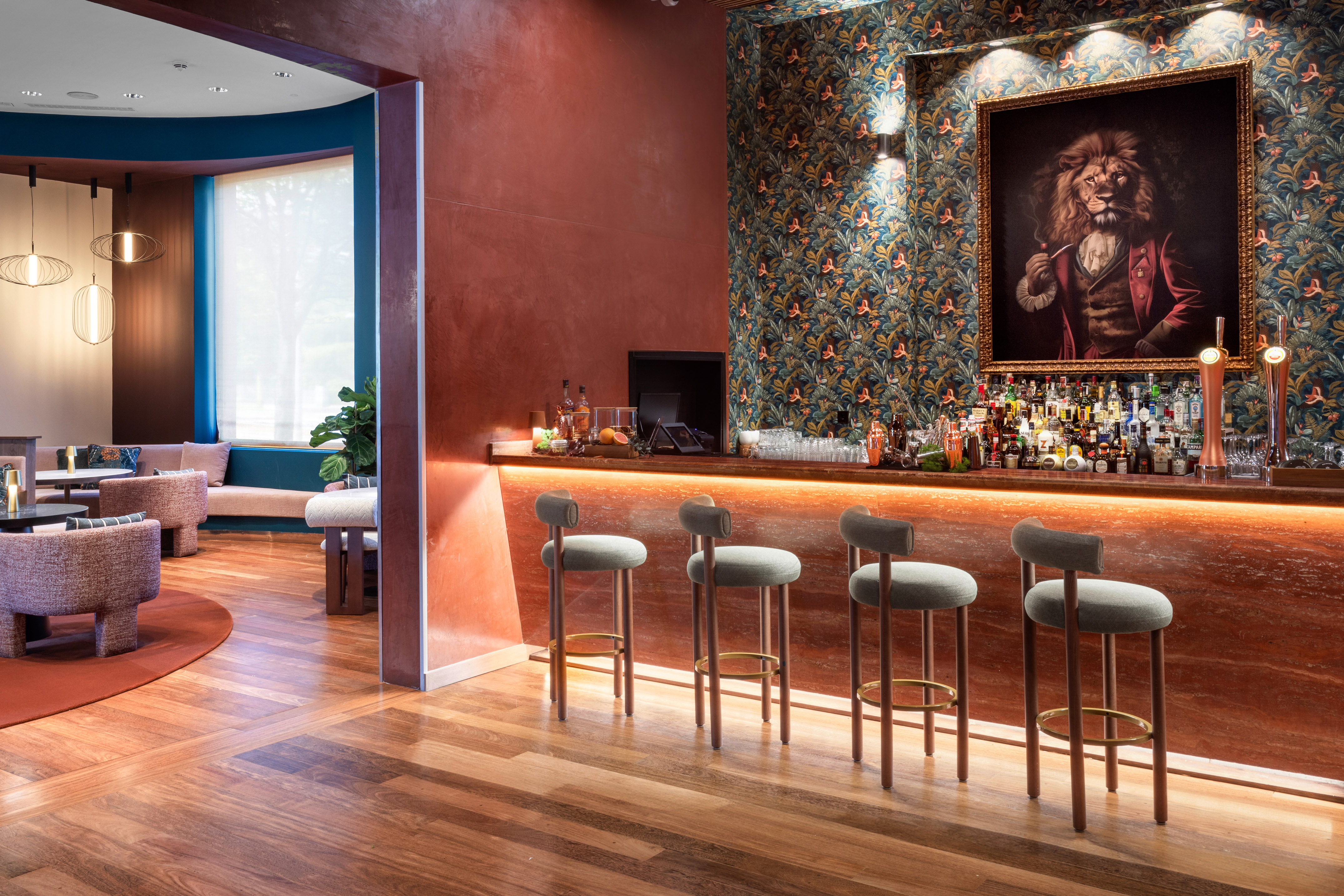 Chic hotel bar interior with lion painting, illuminated counter, and lounge.