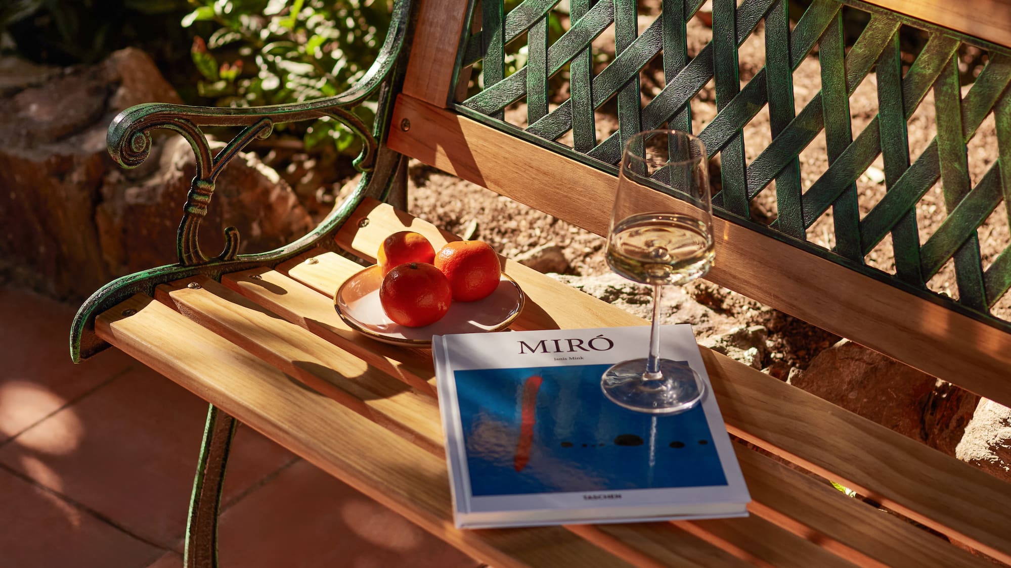 a book and a glass of wine on a bench
