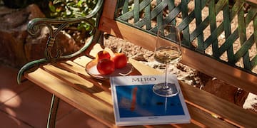 a book and a glass of wine on a bench