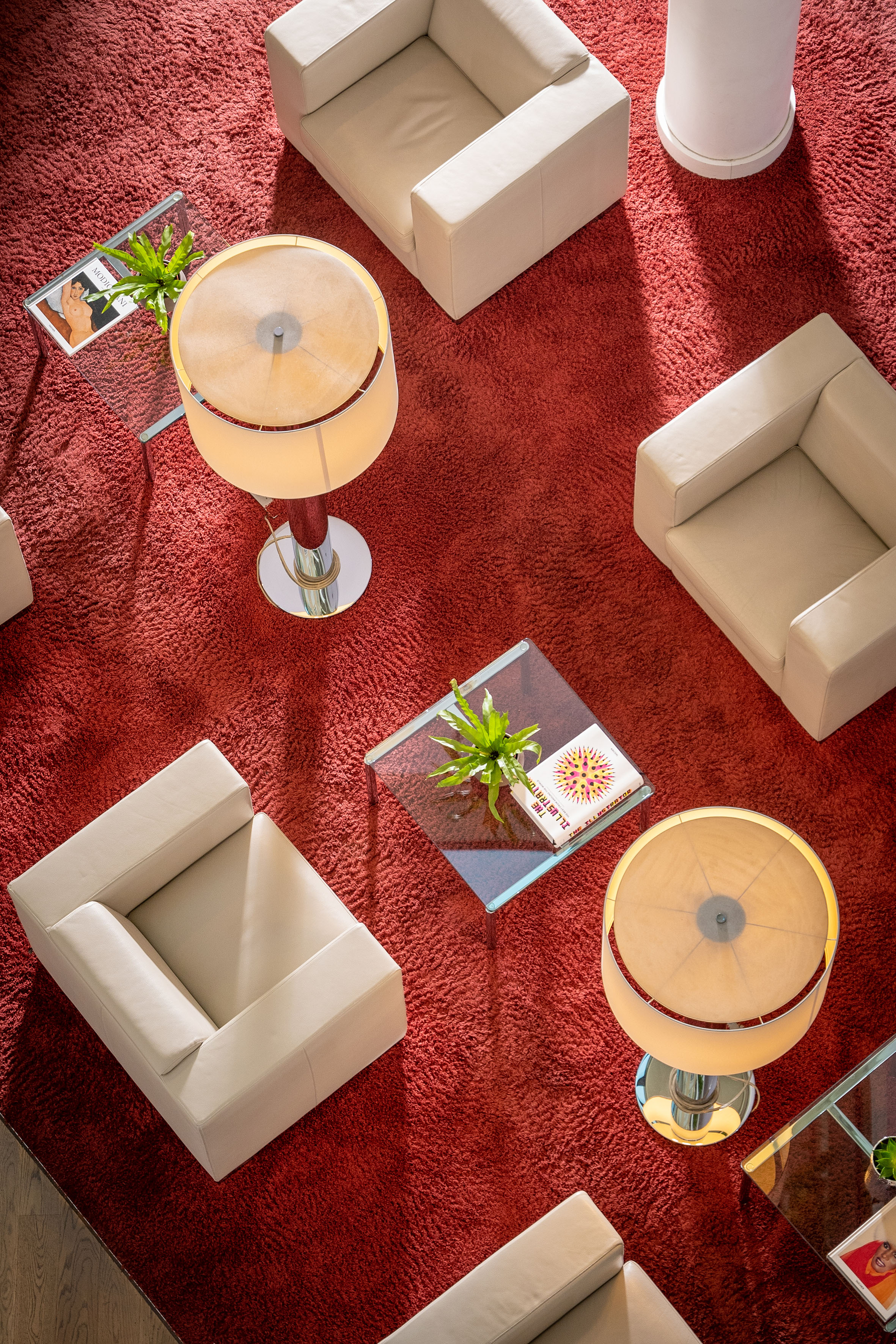 Modern lounge: Red shag rug, beige armchairs, glass coffee tables, ambient lamps.