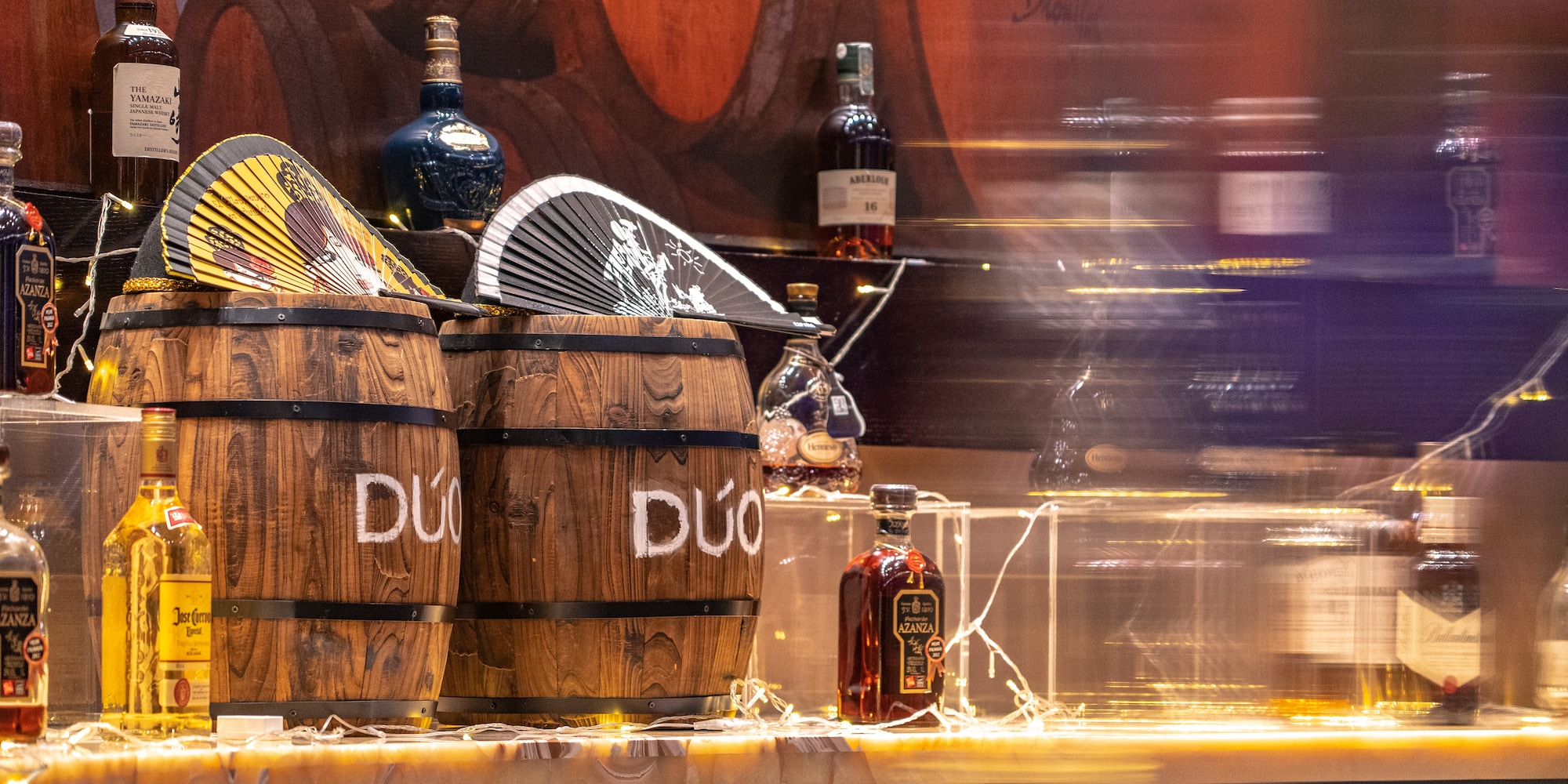 a group of barrels with bottles of liquor on a counter