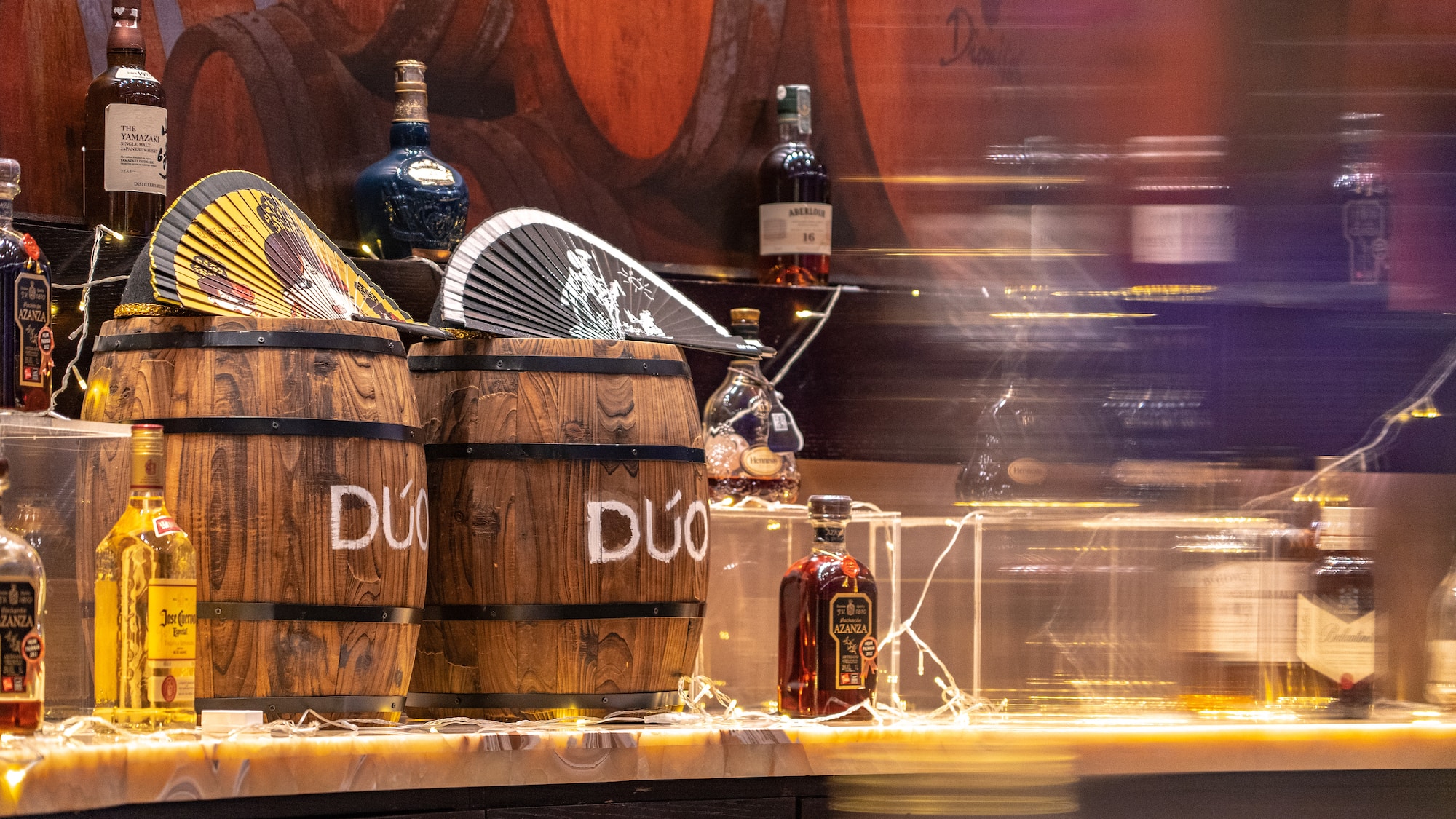 a group of barrels with bottles of liquor on a counter