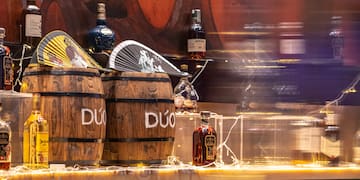a group of barrels with bottles of liquor on a counter