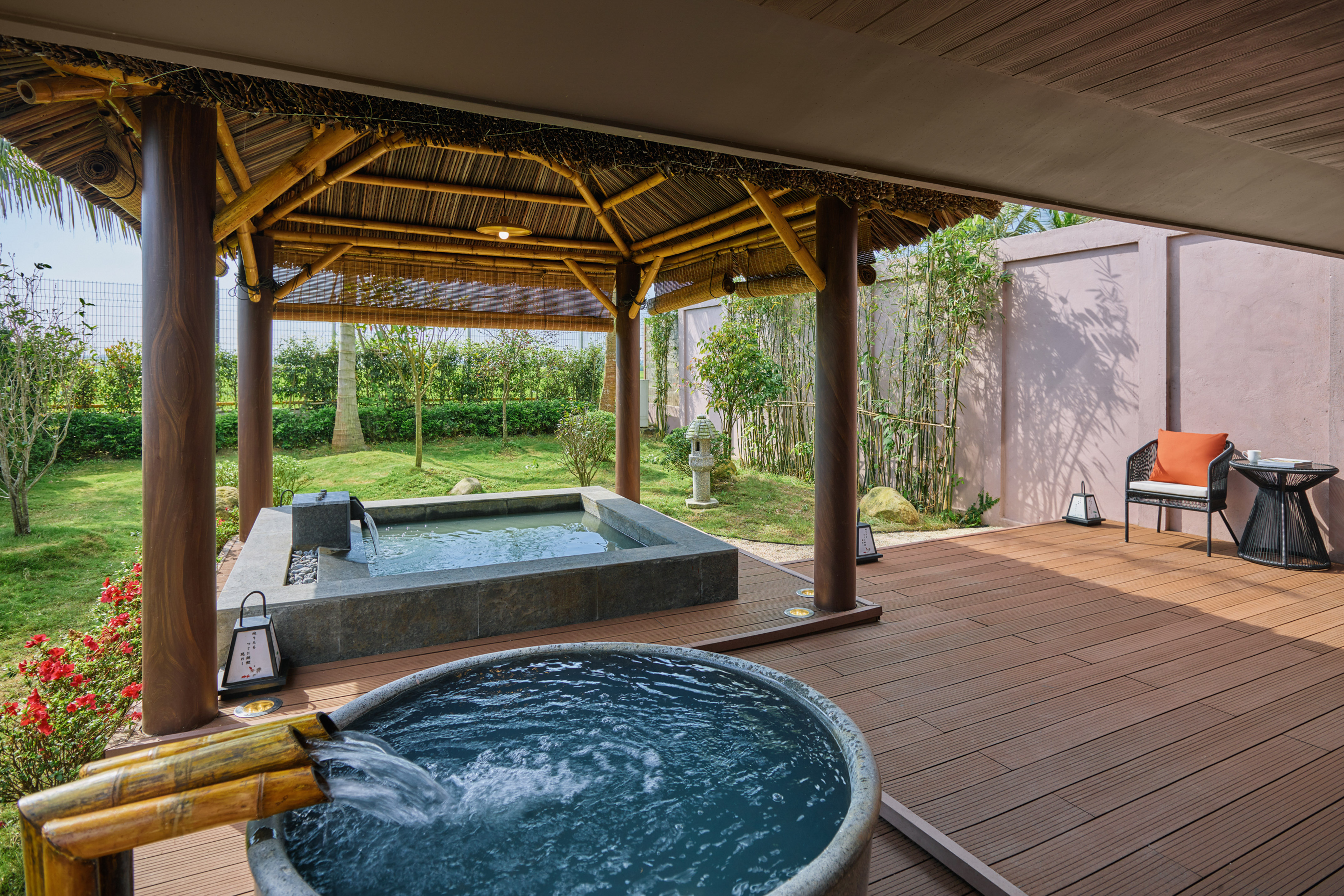 Lush outdoor spa with two hot tubs, bamboo pavilion, and wooden deck.