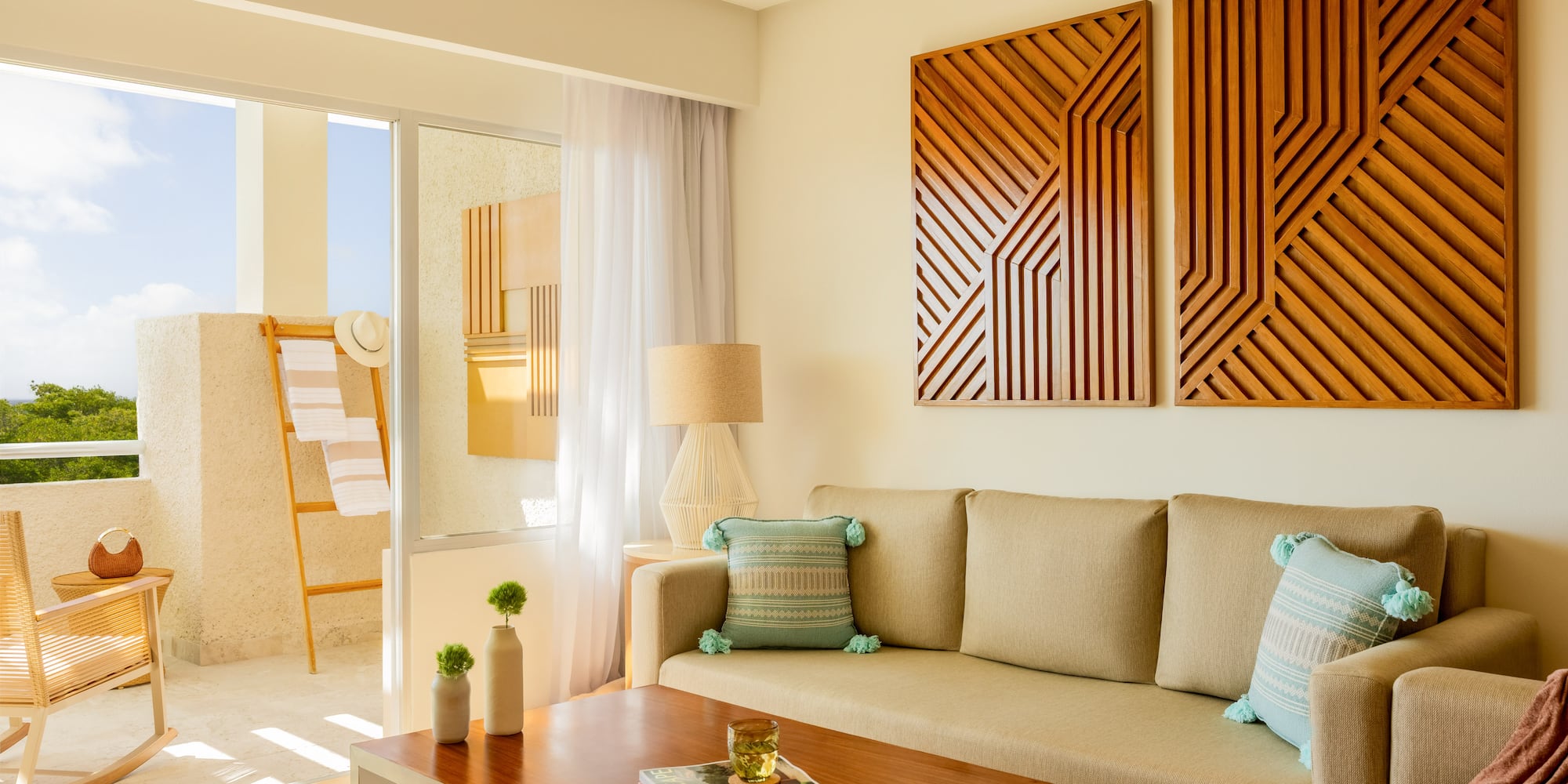 Resort living room with neutral sofa, wood geometric art, and sunny balcony.