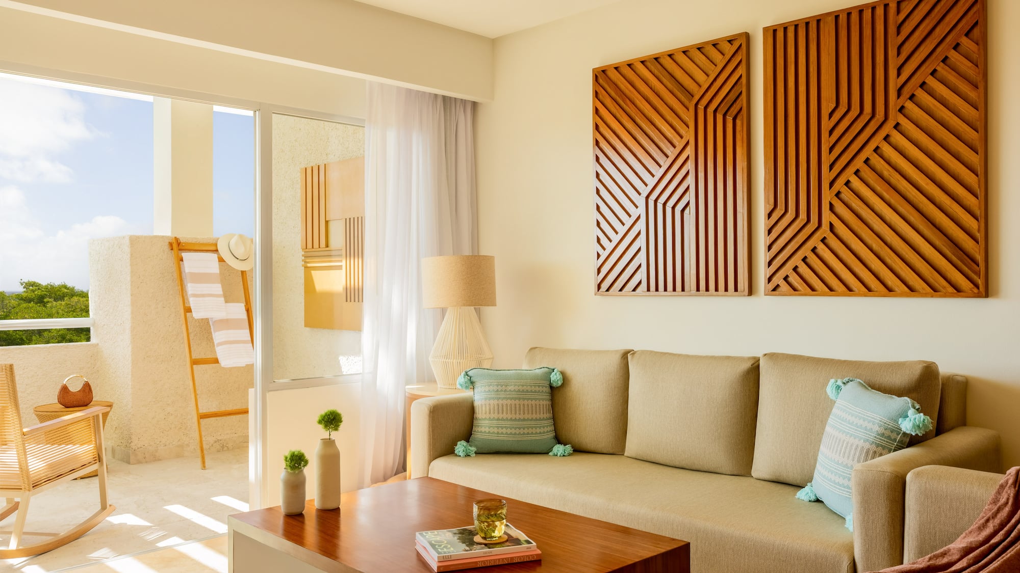 Resort living room with neutral sofa, wood geometric art, and sunny balcony.