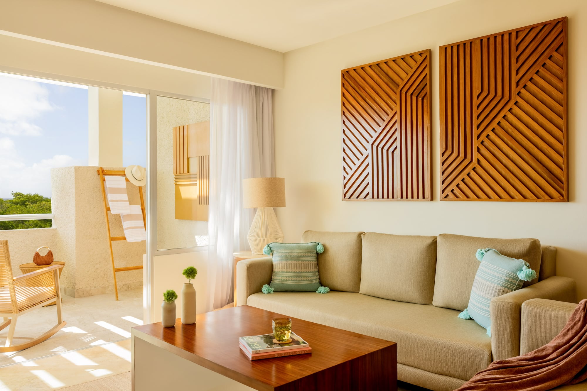 Resort living room with neutral sofa, wood geometric art, and sunny balcony.
