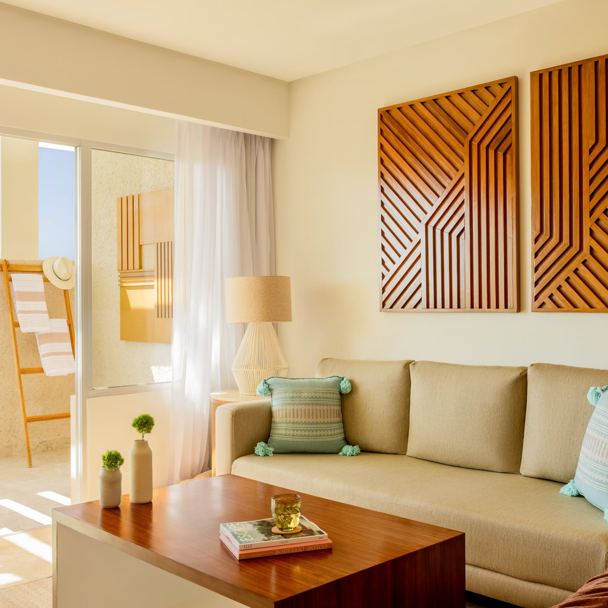Resort living room with neutral sofa, wood geometric art, and sunny balcony.