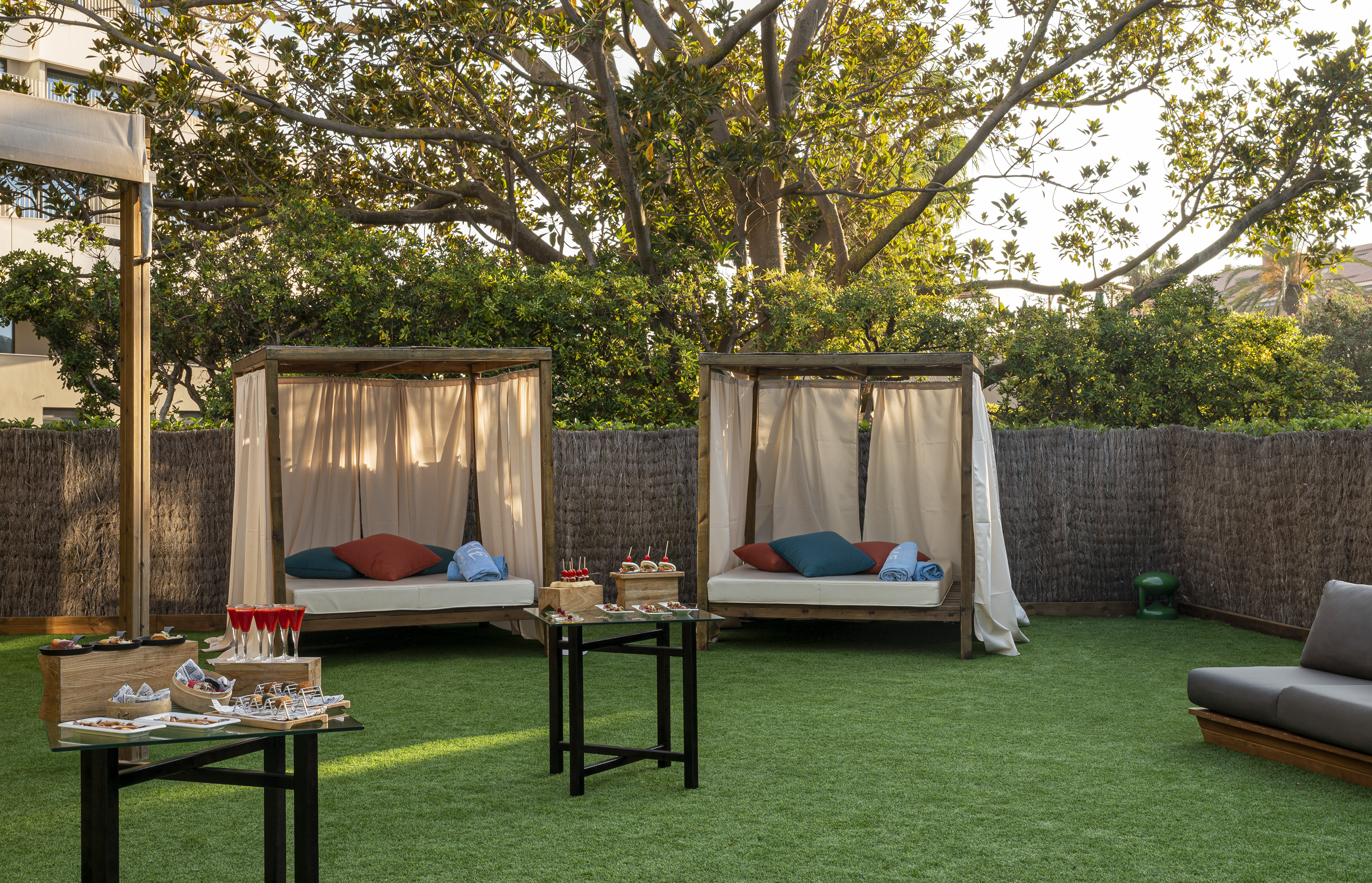 Two private cabanas with snacks on artificial grass in an outdoor lounge area.