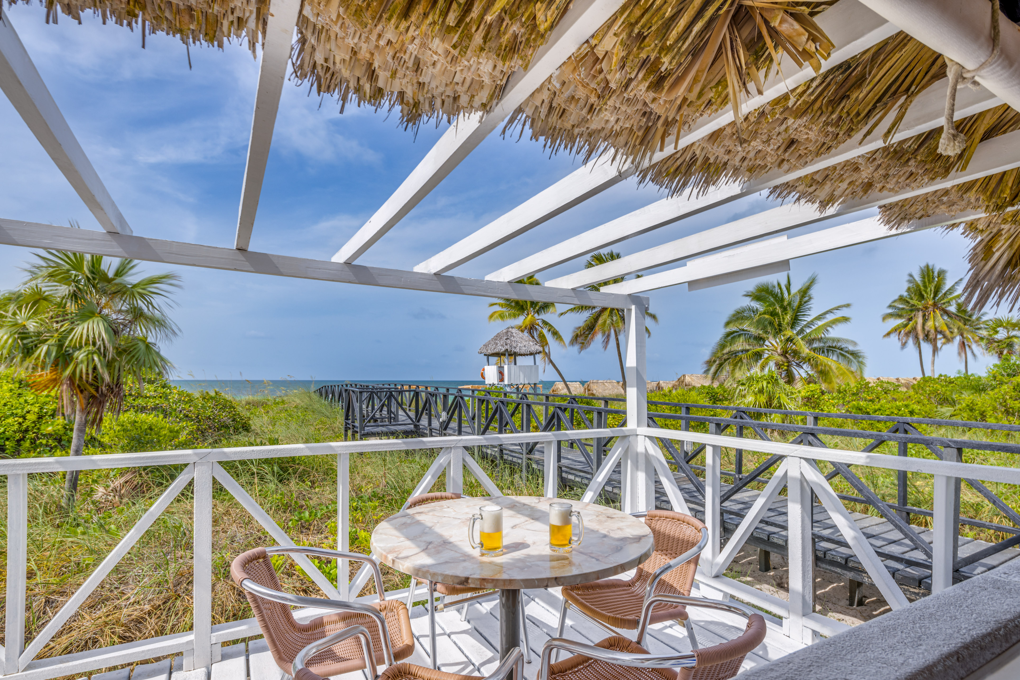 a table and chairs on a deck overlooking a beach
