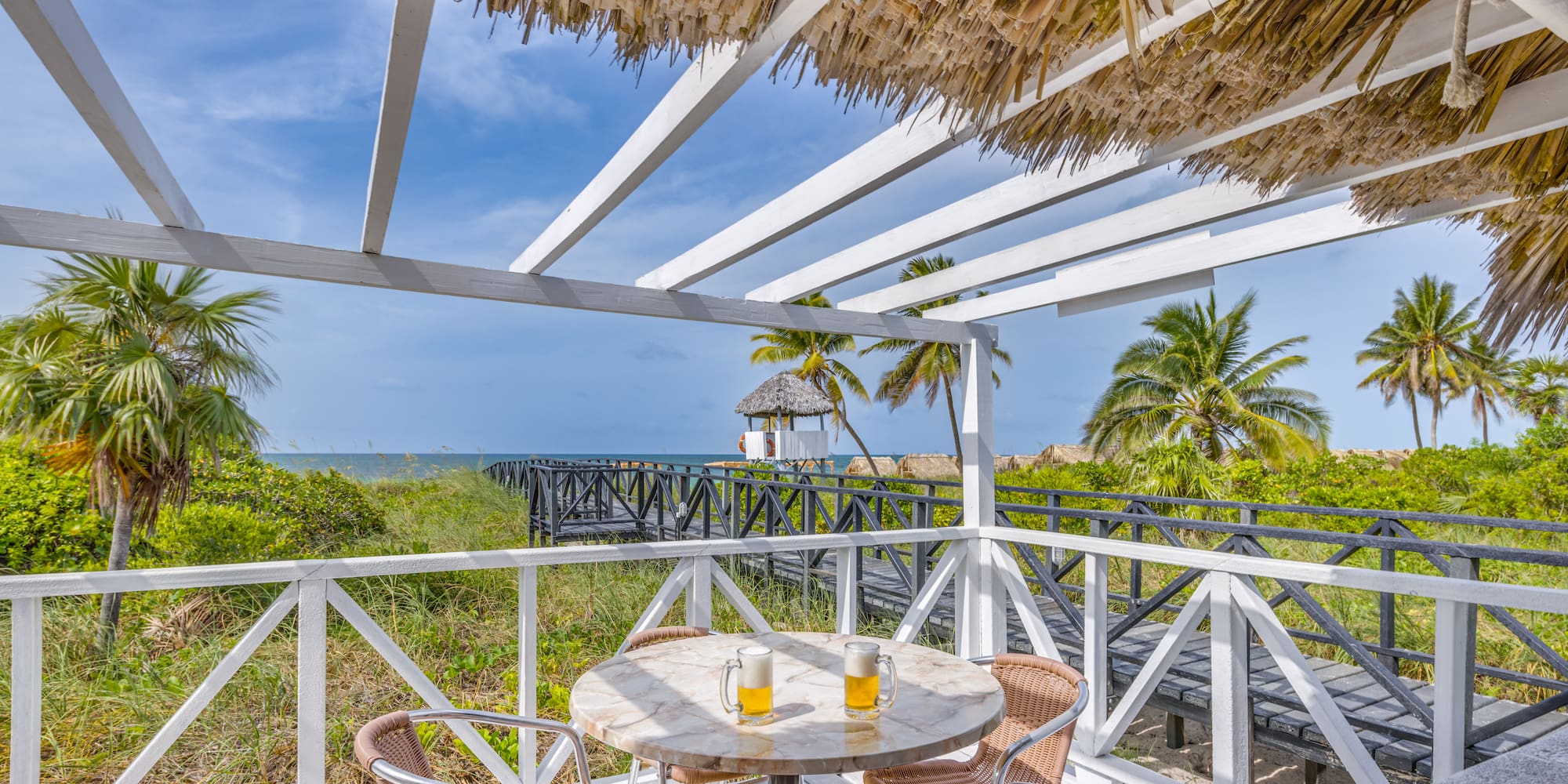 a table and chairs on a deck overlooking a beach