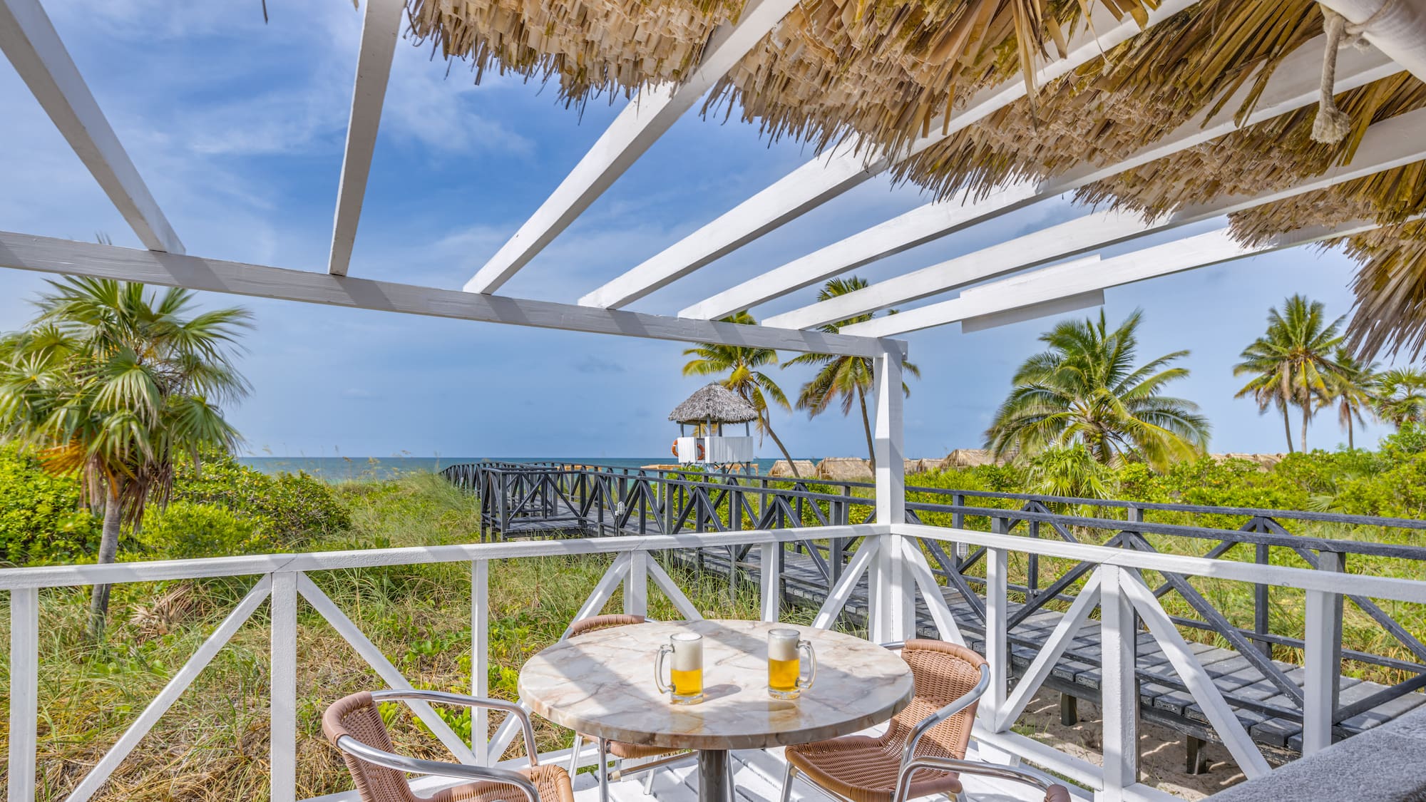 a table and chairs on a deck overlooking a beach