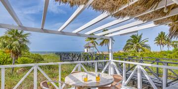 a table and chairs on a deck overlooking a beach