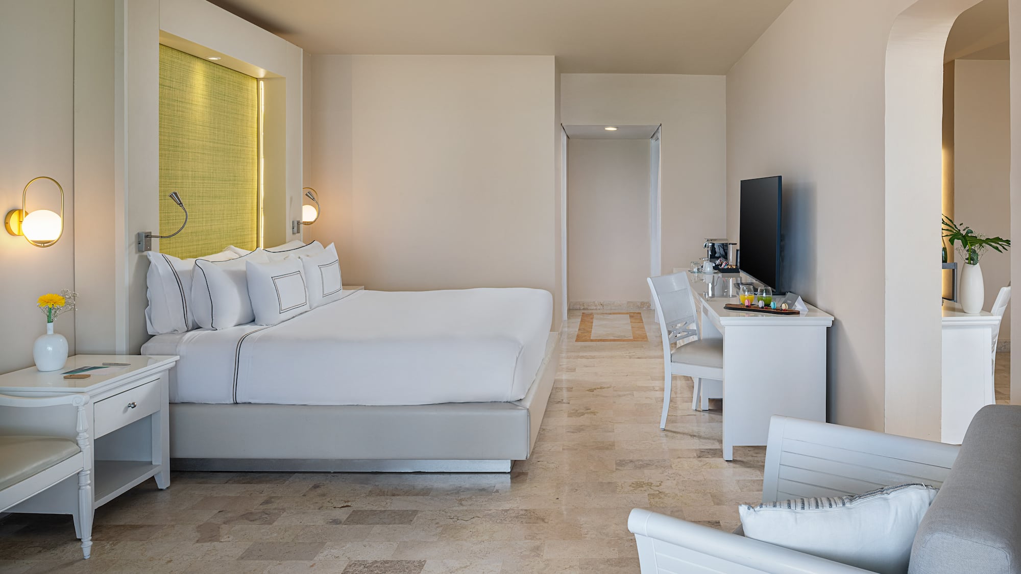 Luxury hotel room with king bed, white linens, elegant design, and TV.