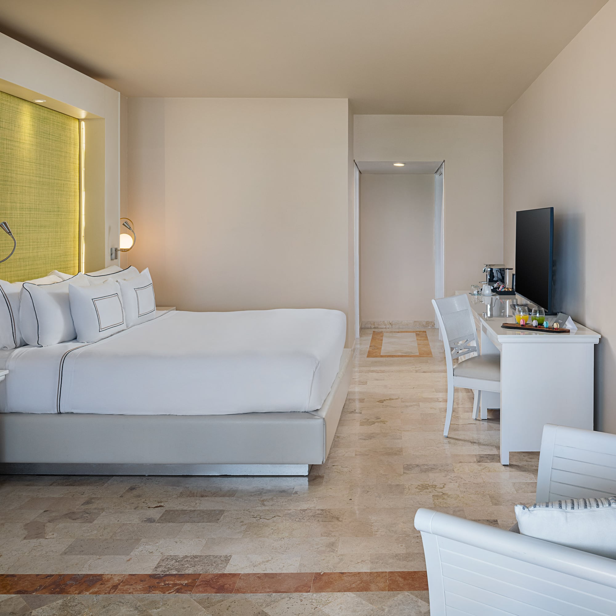 Luxury hotel room with king bed, white linens, elegant design, and TV.