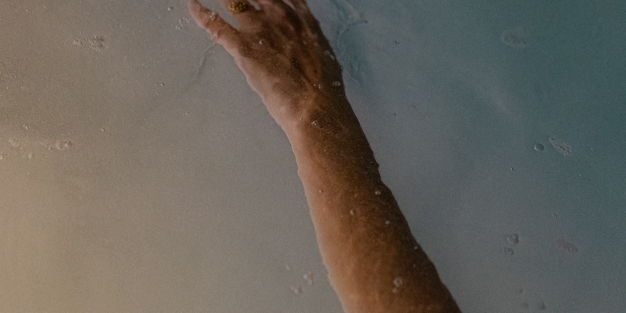 a person's hand reaching out to the water