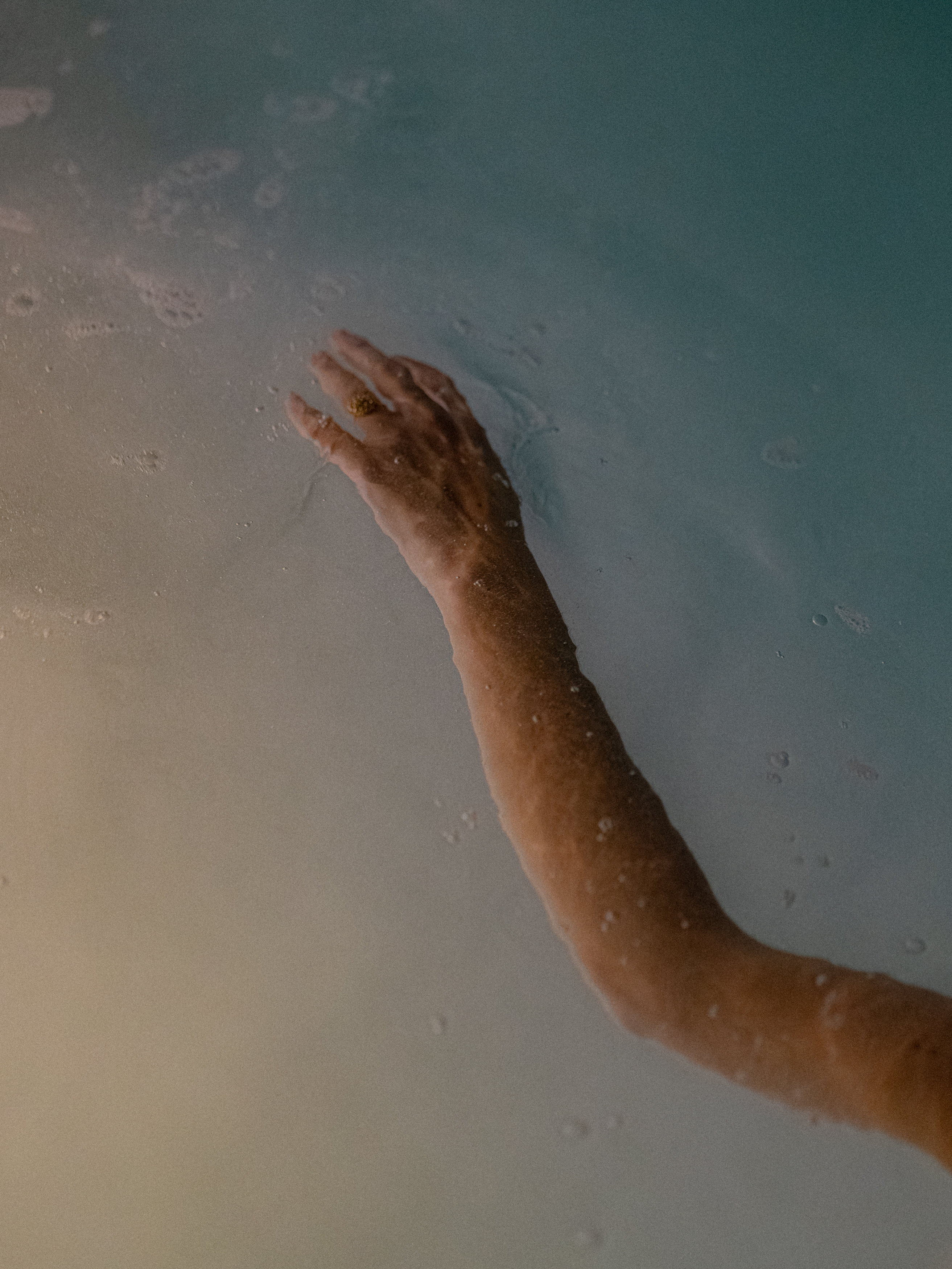 a person's hand reaching out to the water